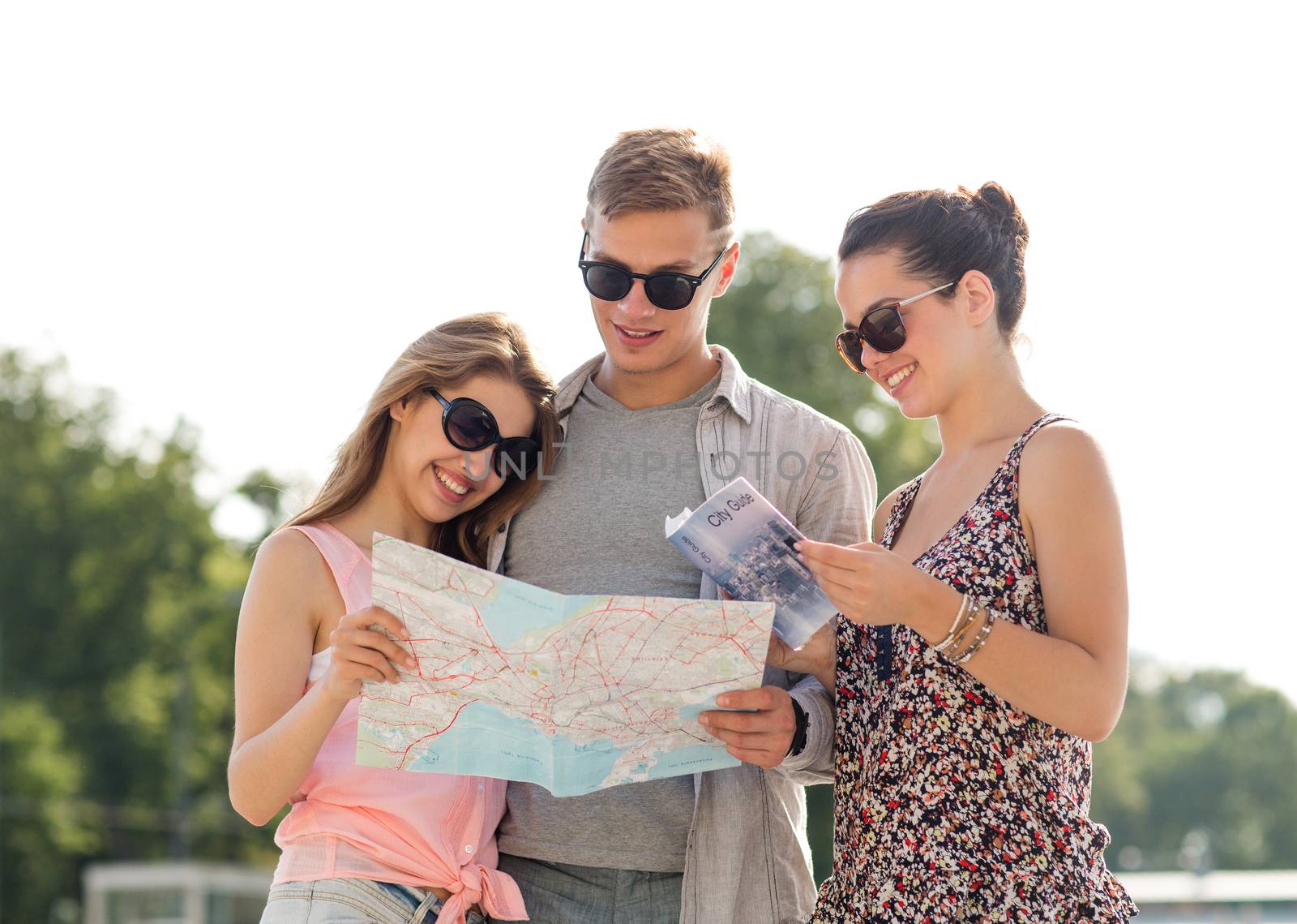 friendship, travel, tourism, vacation and people concept - smiling friends with map and city guide outdoors