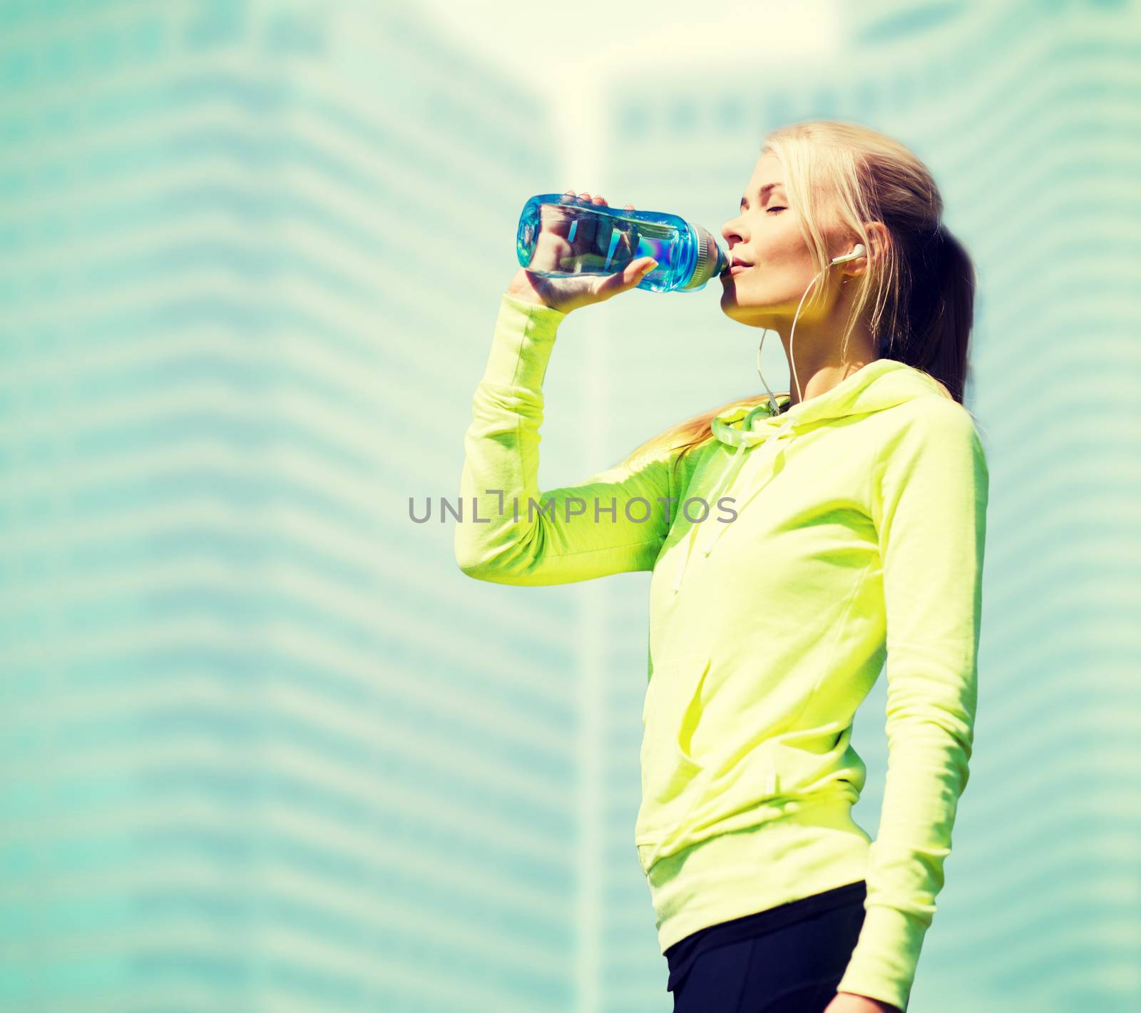 woman drinking water after doing sports outdoors by dolgachov