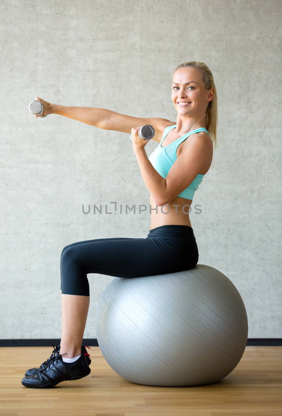 smiling woman with dumbbells and exercise ball by dolgachov
