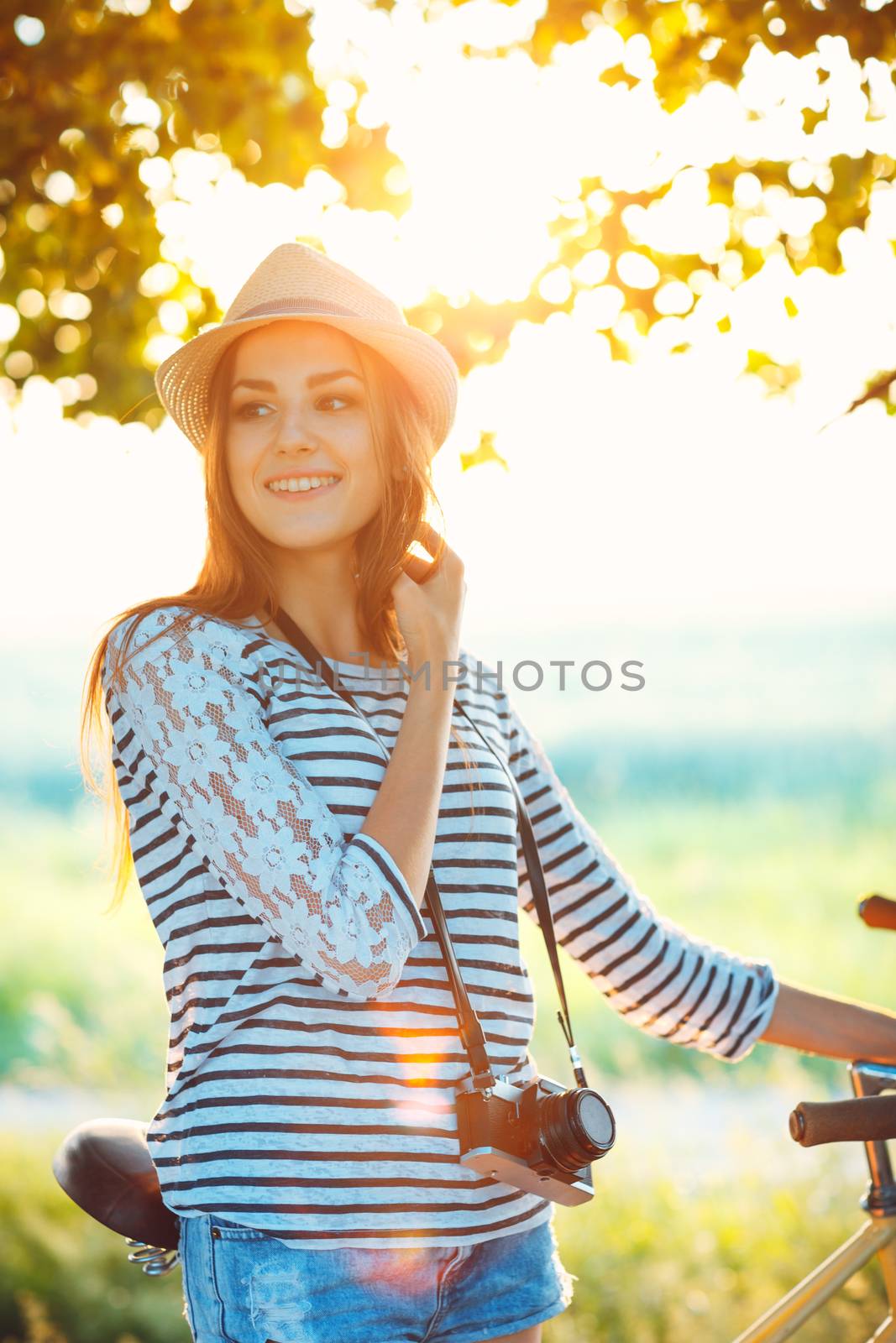 Lovely young woman in a hat riding a bicycle outdoors. Active pe by vlad_star