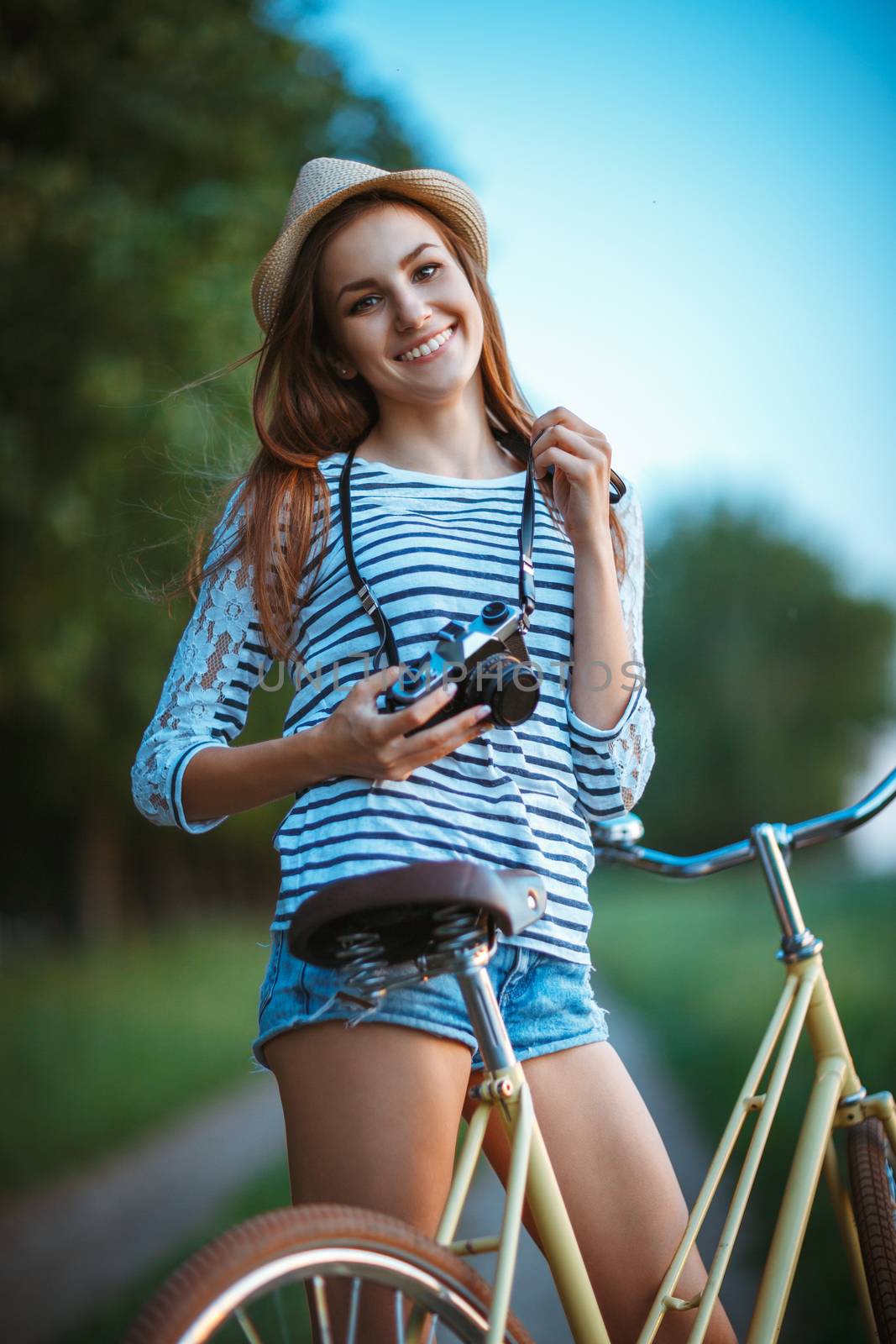 Lovely young woman in a hat with a bicycle outdoors by vlad_star