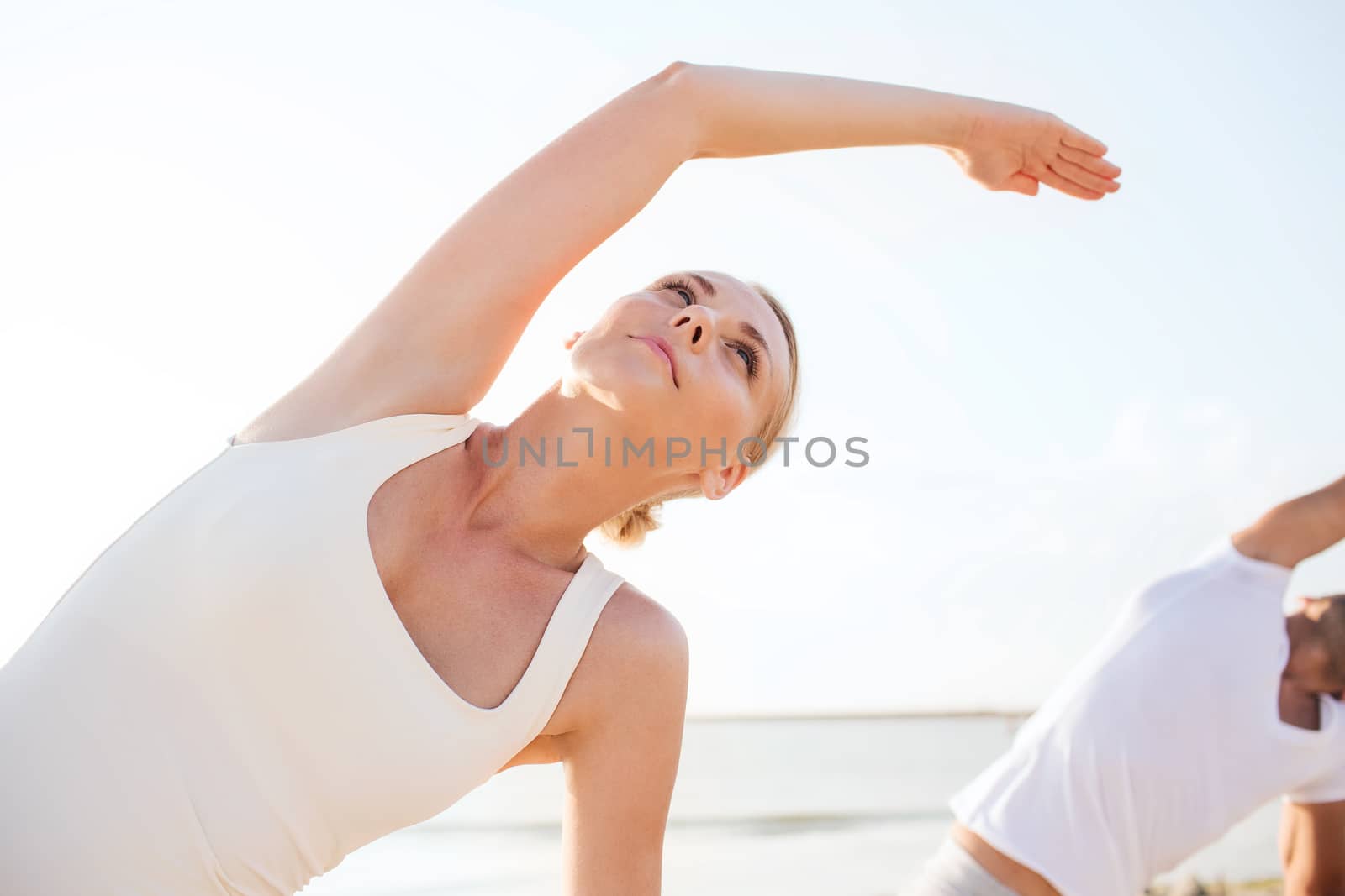 fitness, sport, friendship and lifestyle concept - close up of woman and man making yoga exercises on beach