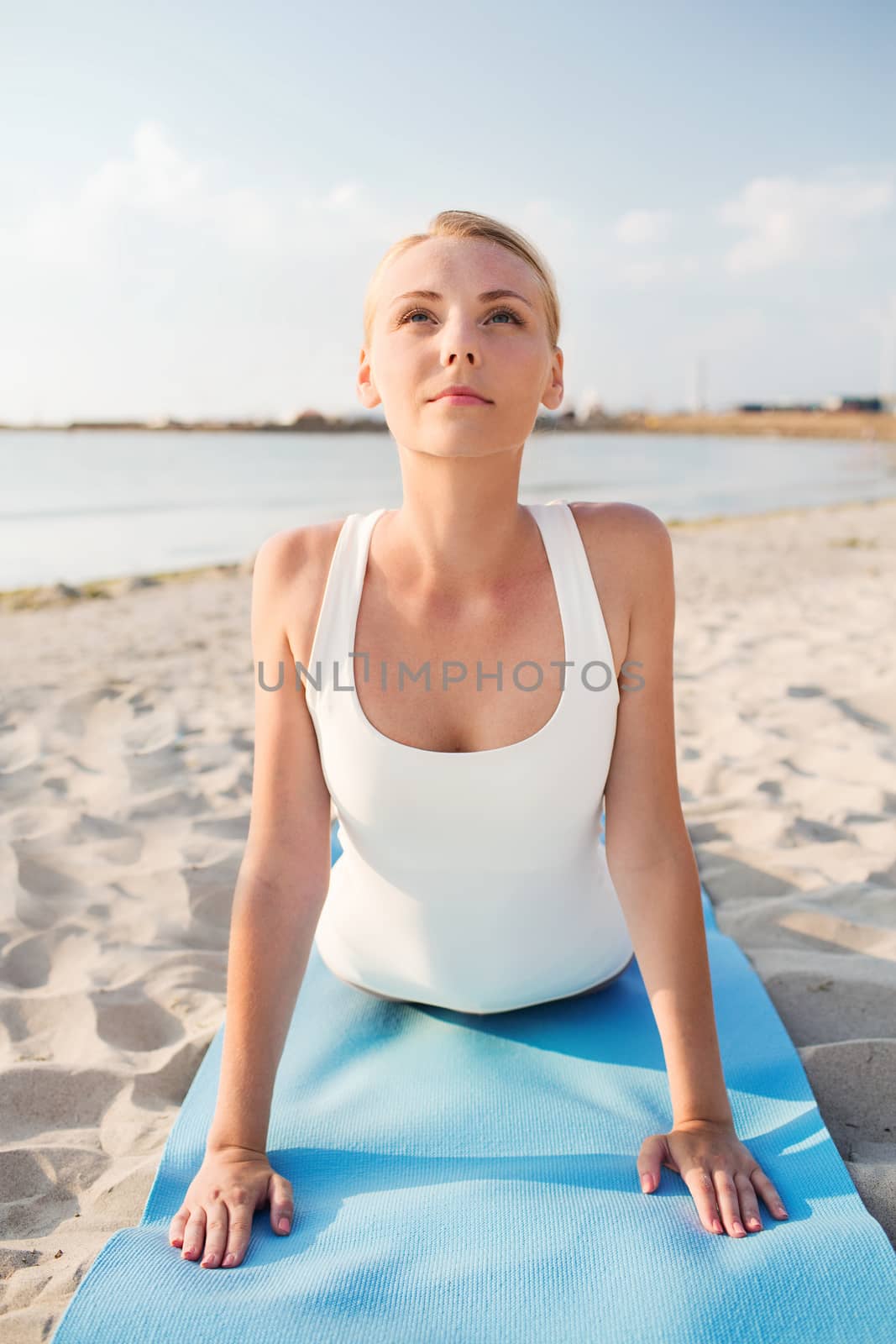 young woman making yoga exercises outdoors by dolgachov