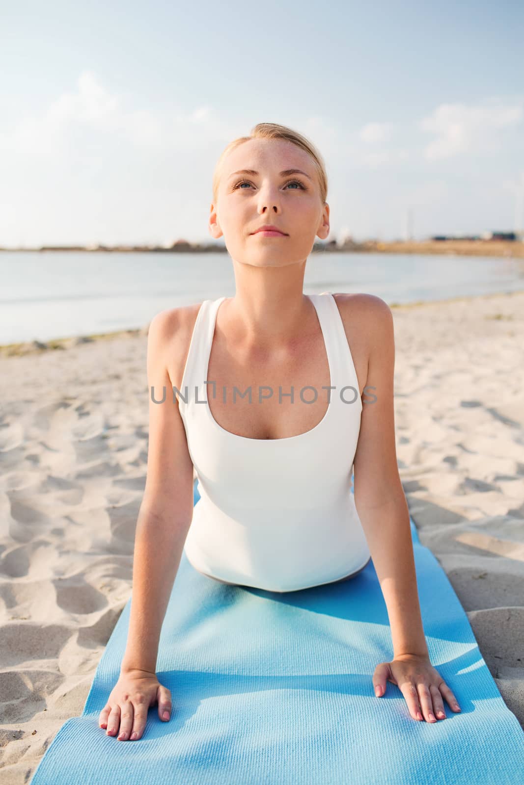 fitness, sport, people and lifestyle concept - young woman making yoga exercises lying mat outdoors