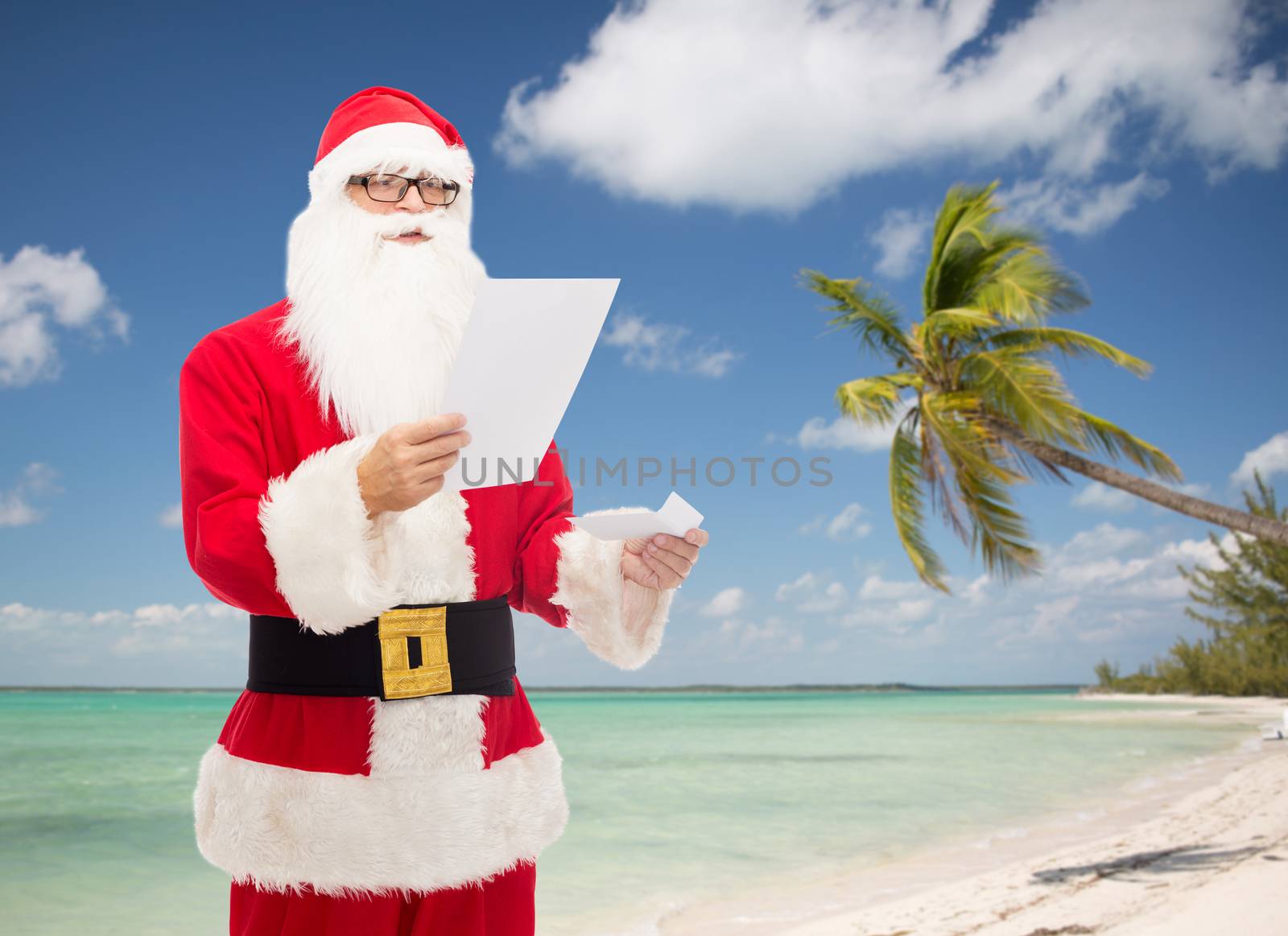 christmas, holidays, travel and people concept - man in costume of santa claus reading letter