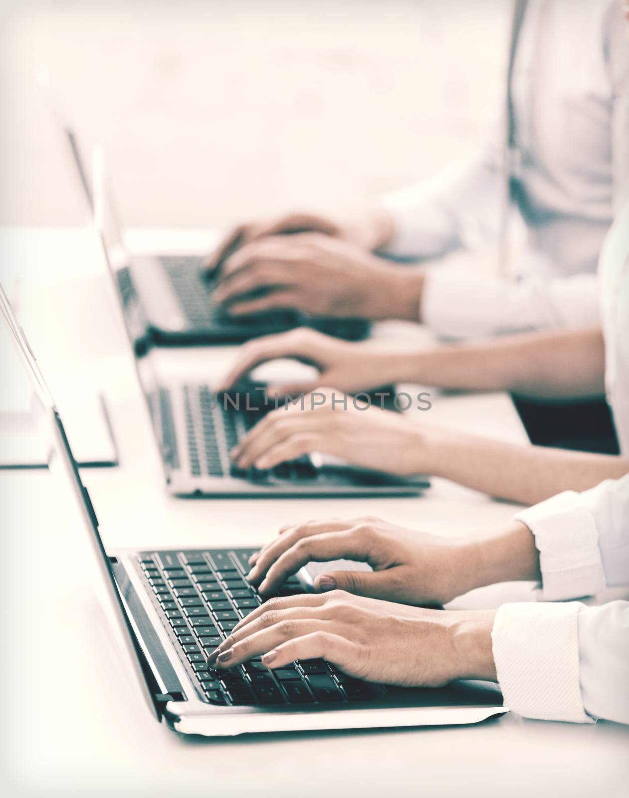 business, school and education concept - group of people working with laptops in office