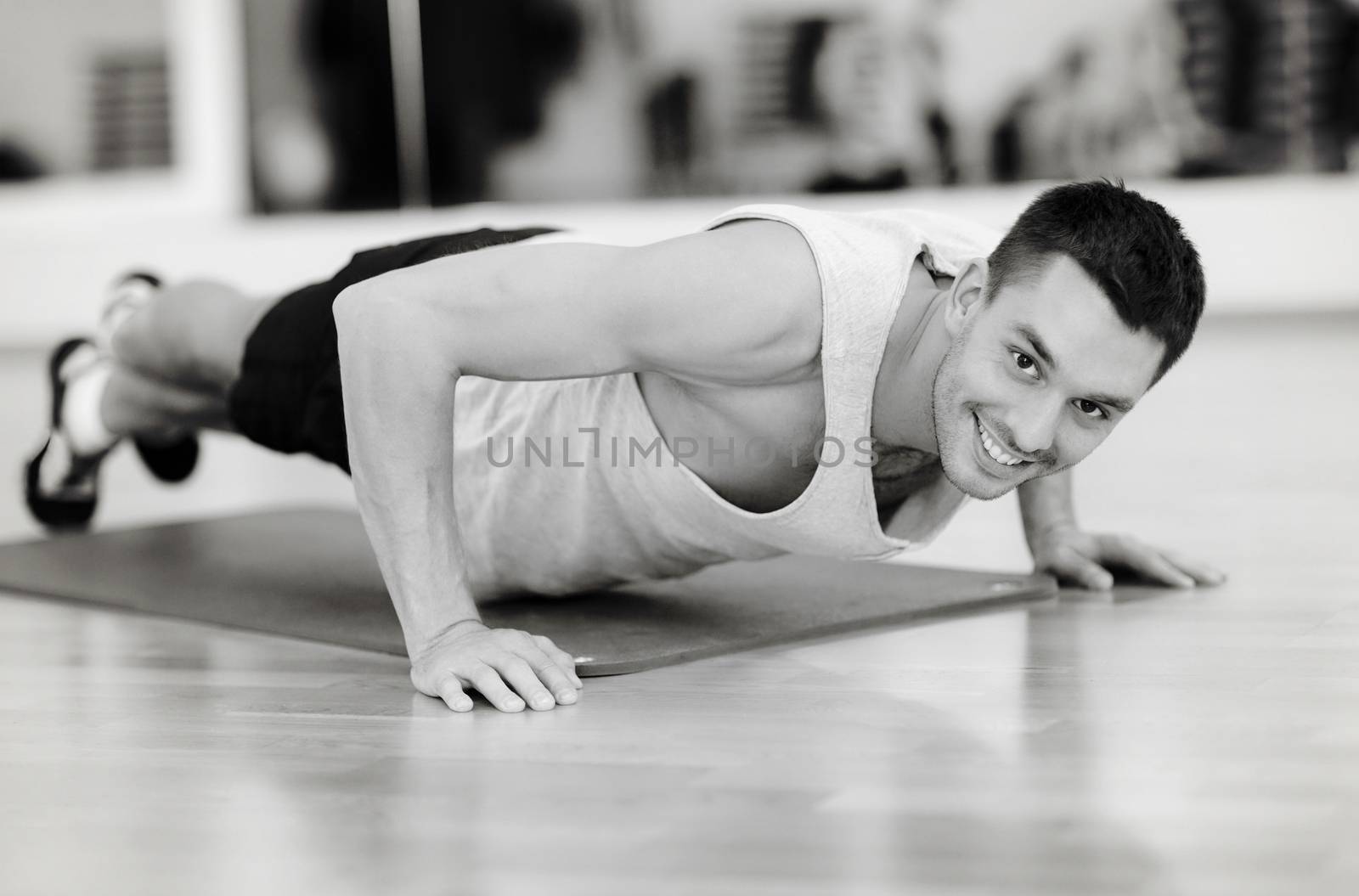 smiling man doing push-ups in the gym by dolgachov