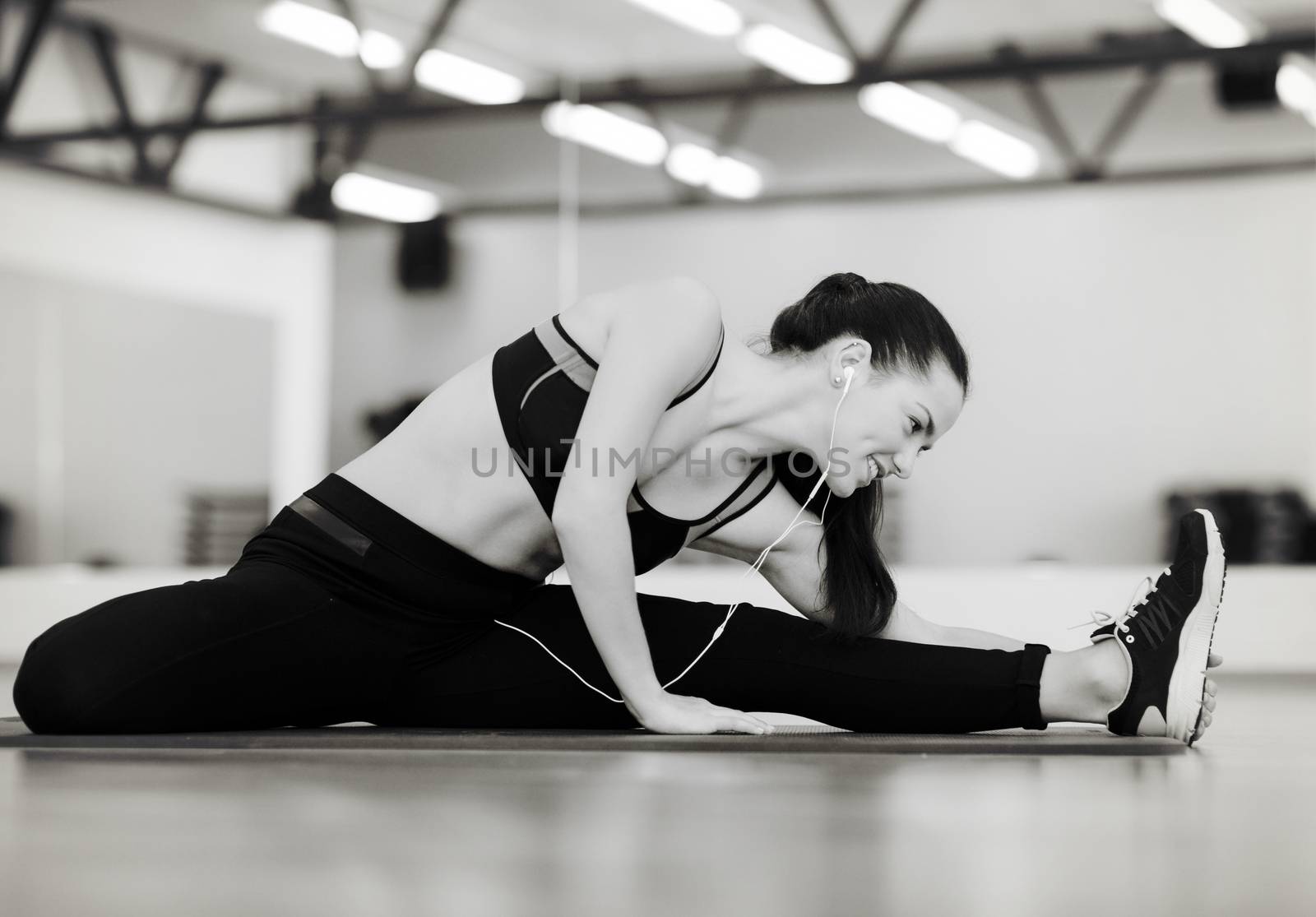 smiling woman stretching on mat in the gym by dolgachov