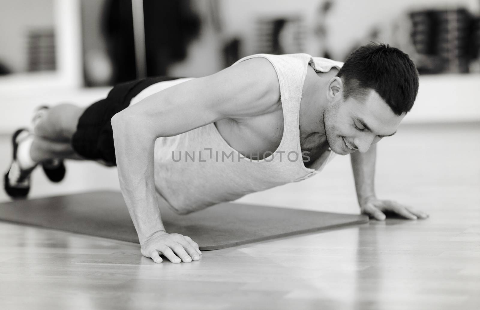 smiling man doing push-ups in the gym by dolgachov