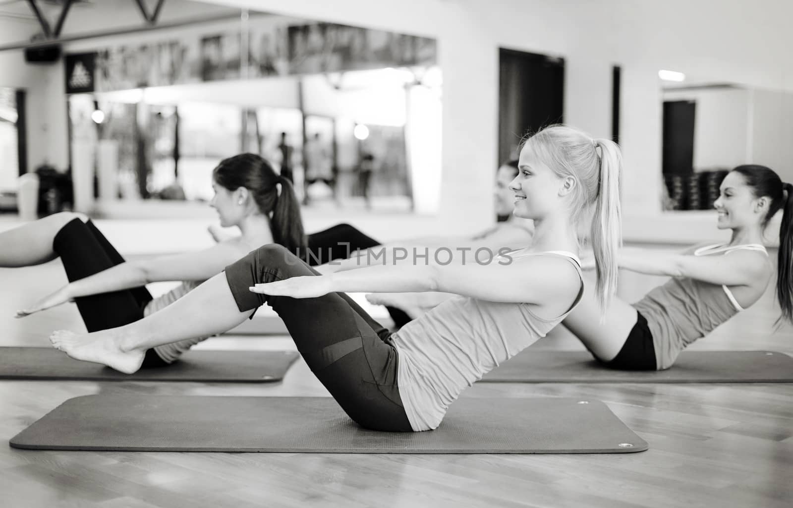 group of smiling women exercising in the gym by dolgachov