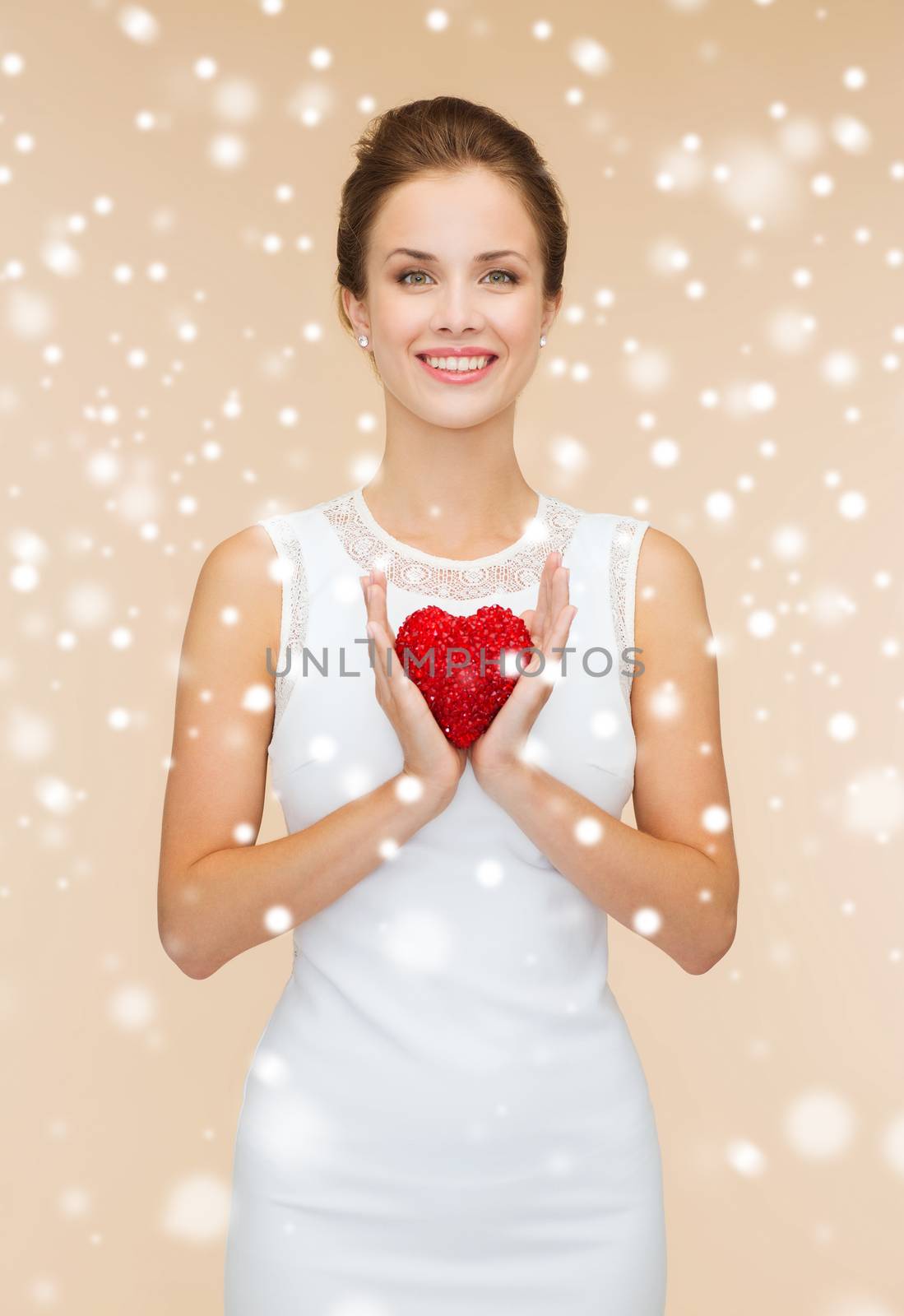 people, holidays, charity and love concept - smiling woman in white dress with red heart over beige background