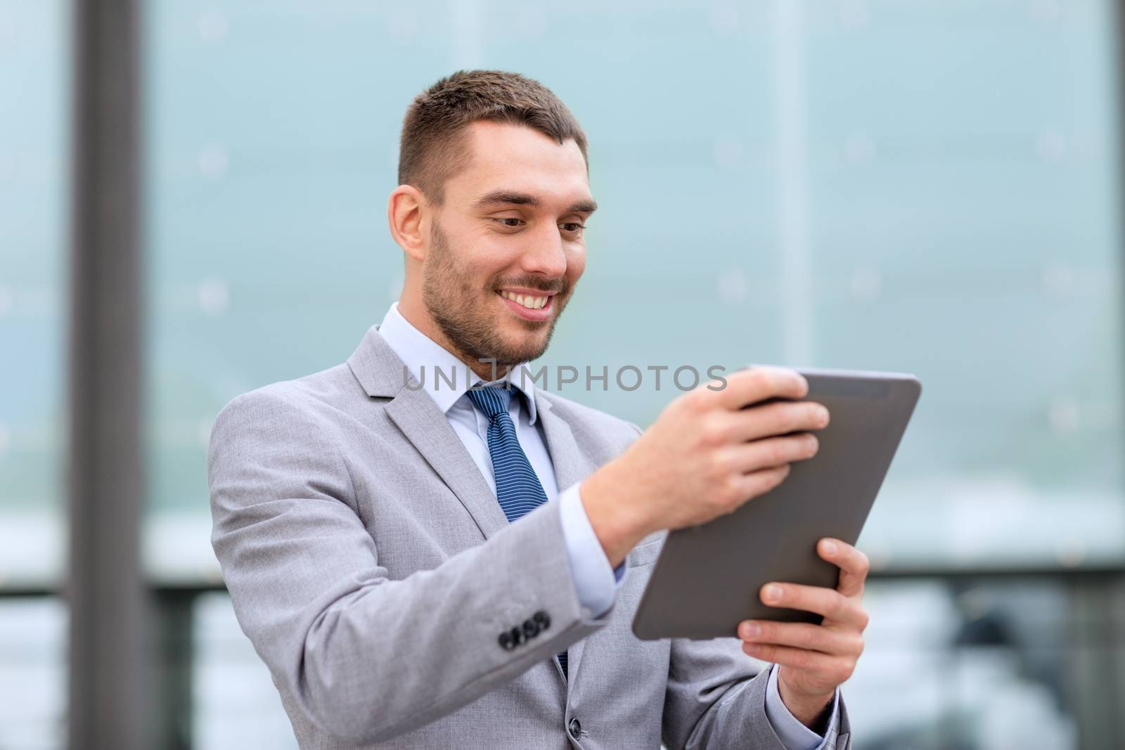 smiling businessman with tablet pc outdoors by dolgachov