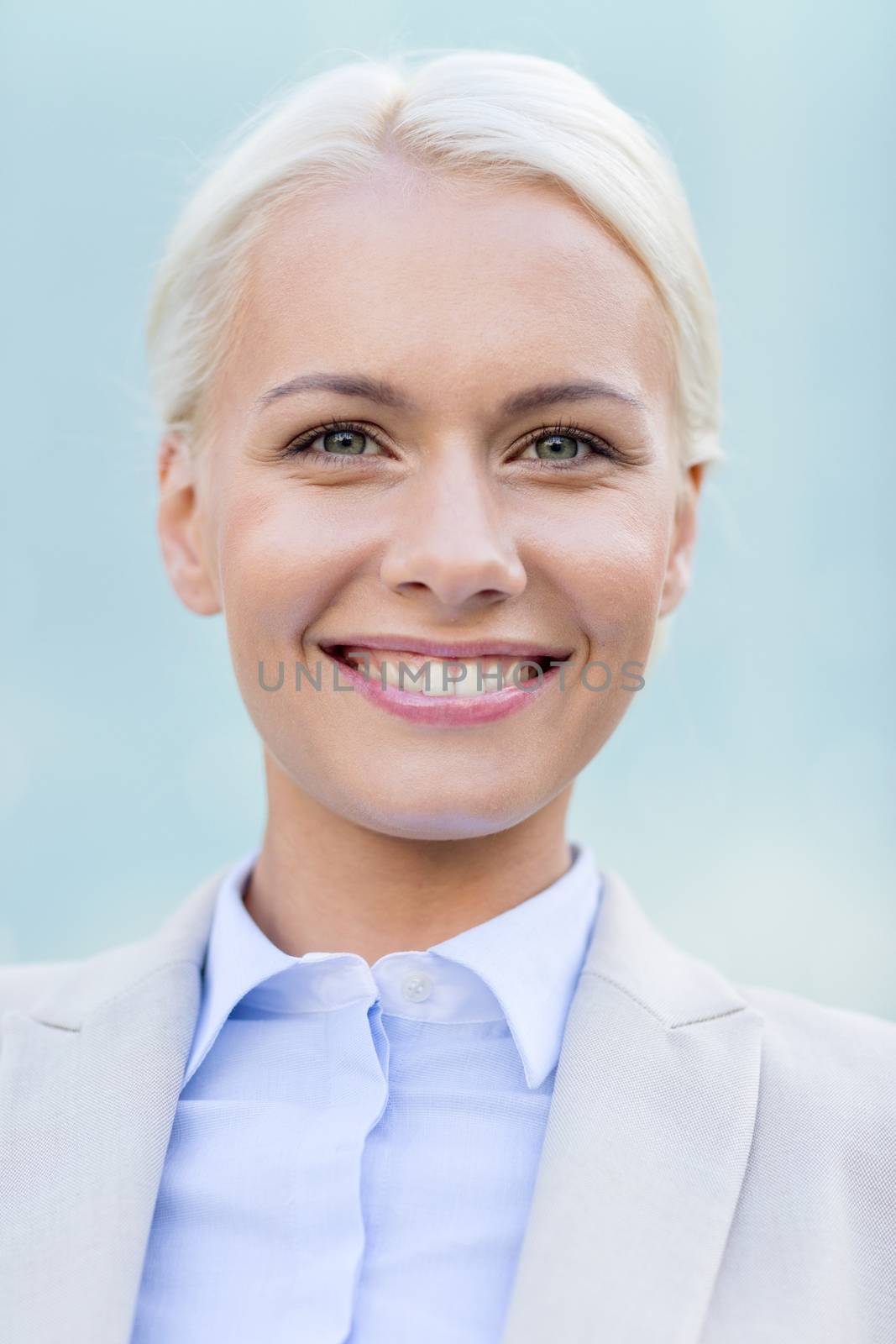 business, people and education concept - young smiling businesswoman over office building