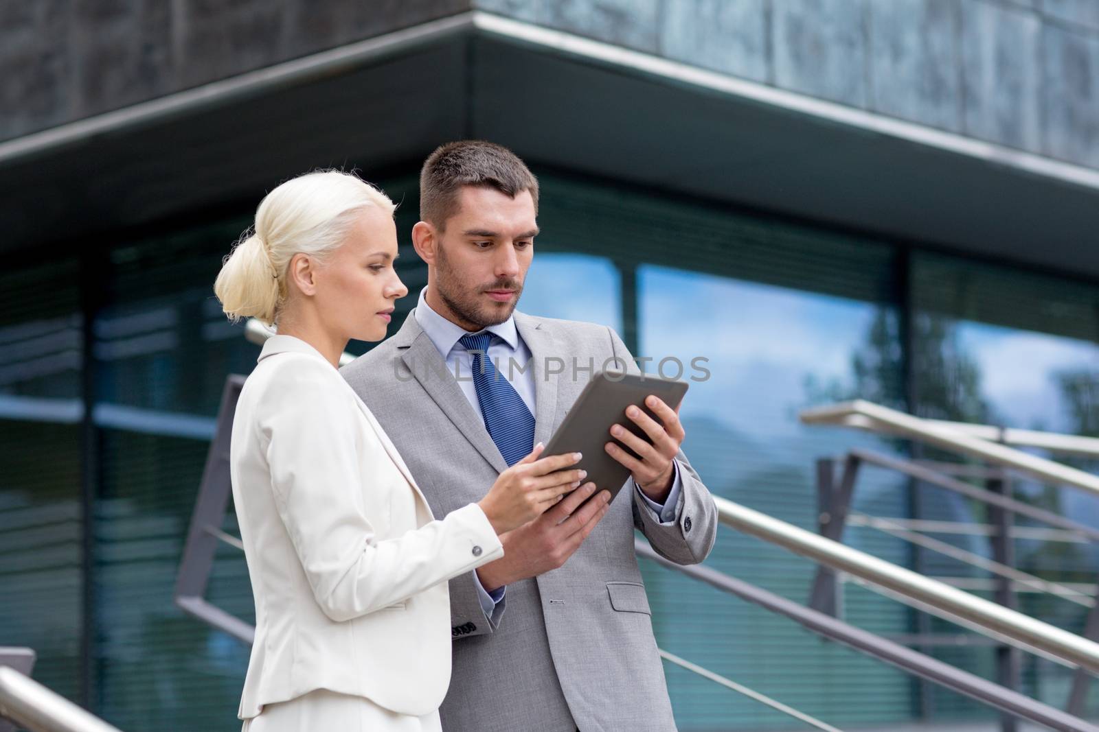 business, partnership, technology and people concept - businessman and businesswoman working with tablet pc computer on city street