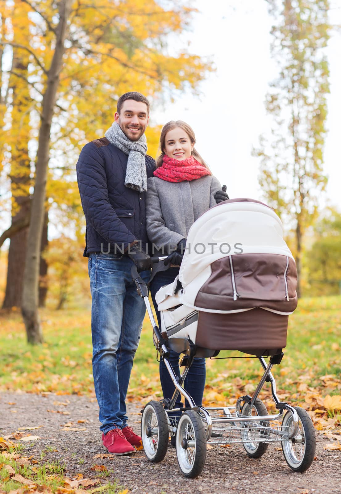 smiling couple with baby pram in autumn park by dolgachov