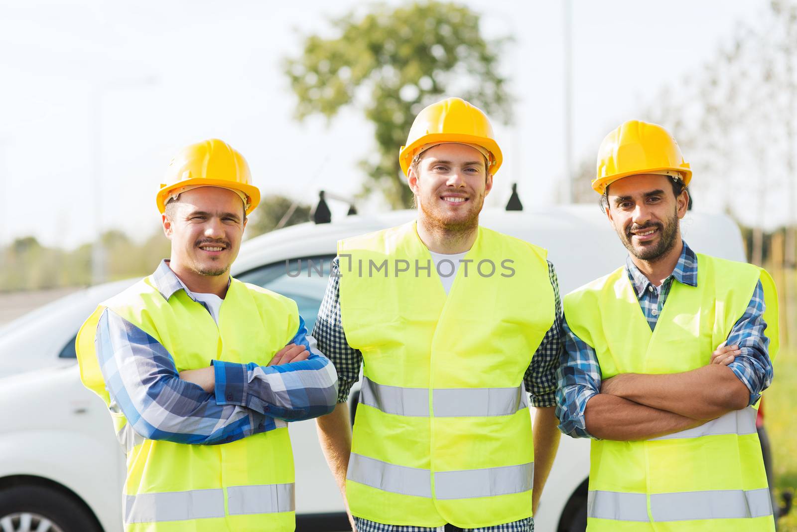 business, building, teamwork and people concept - group of smiling builders in hardhats on car background outdoors