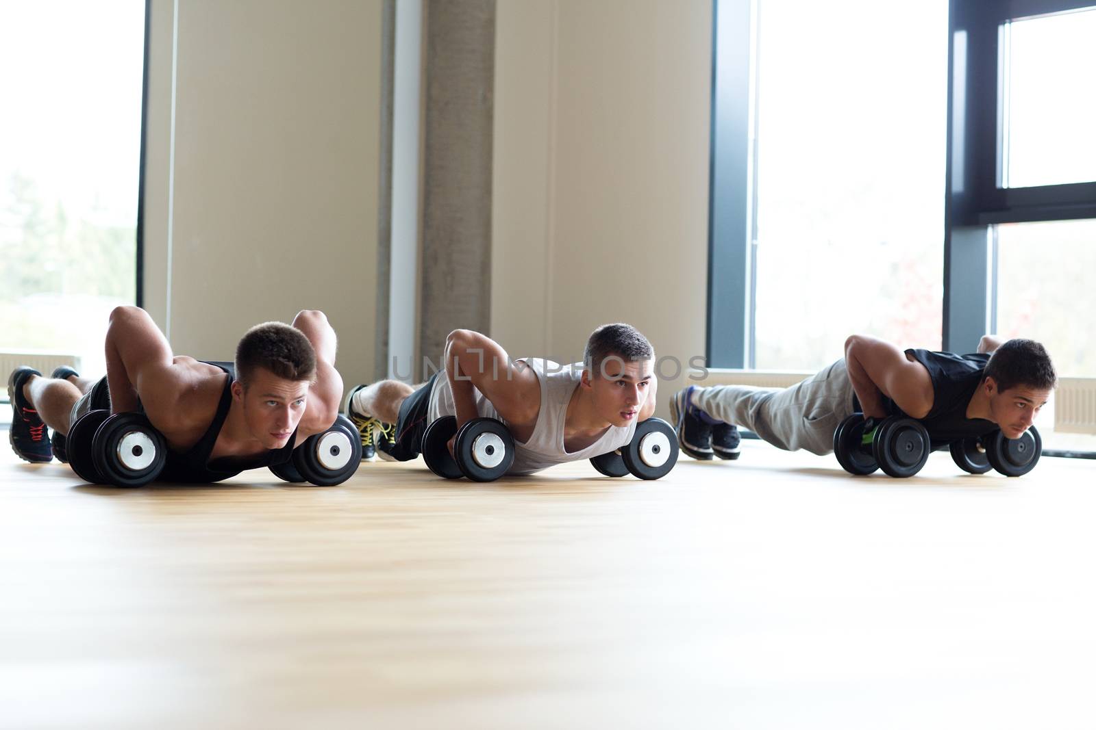 group of men with dumbbells in gym by dolgachov