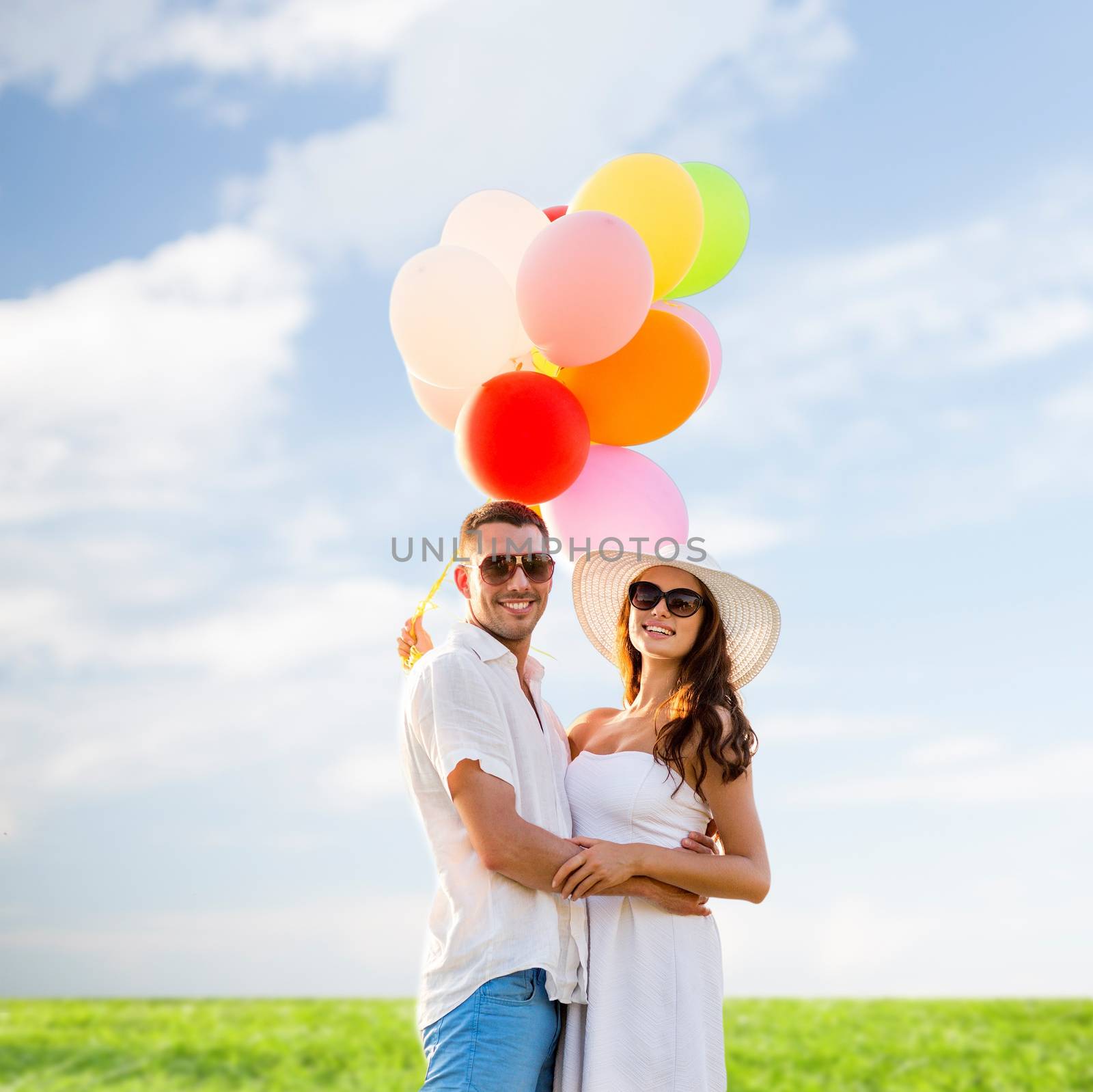 love, wedding, summer, dating and people concept - smiling couple wearing sunglasses with balloons hugging over blue sky and grass background