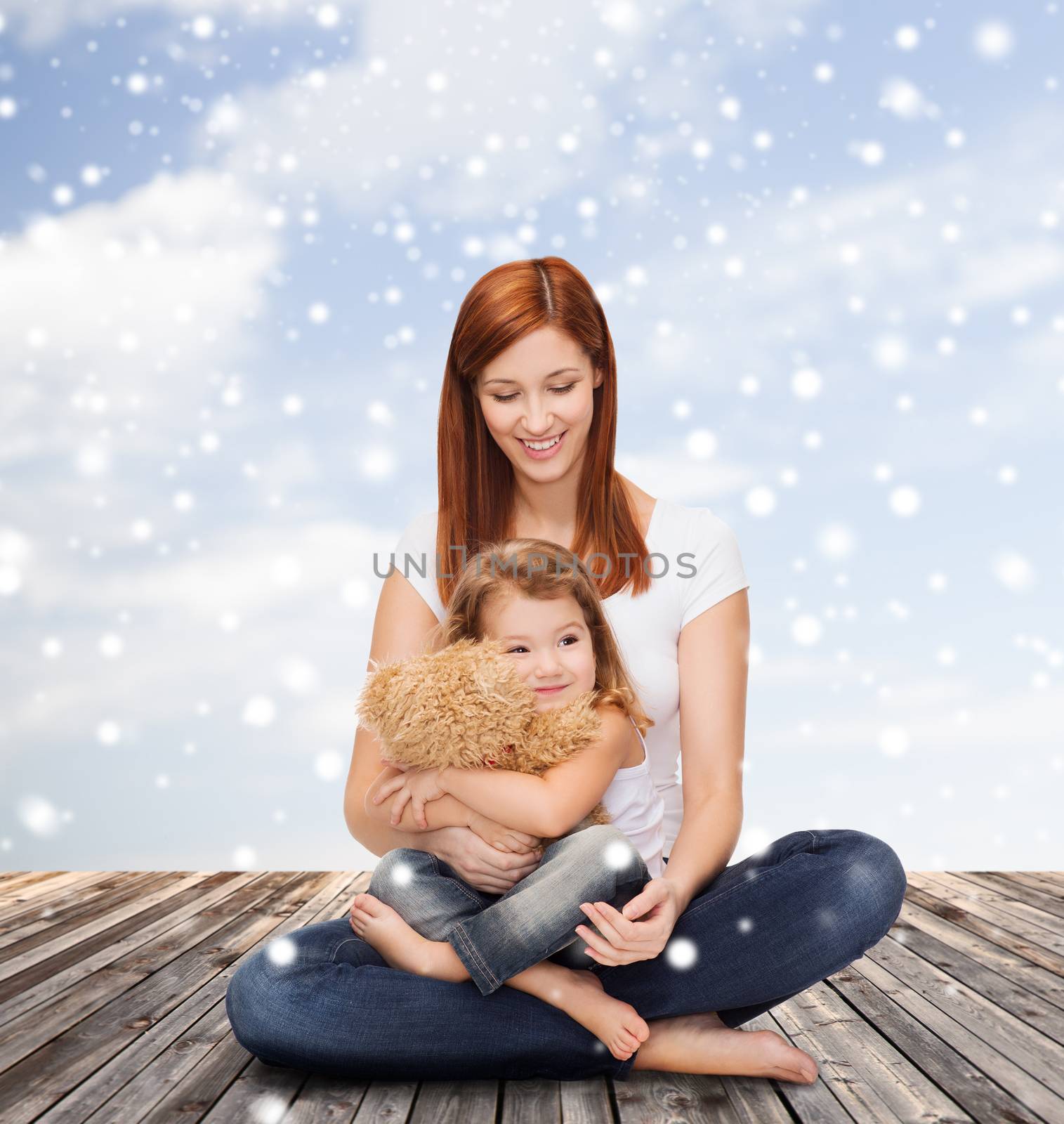 childhood, parenting and people concept - happy mother with little girl and teddy bear toy over wooden floor and blue sky background