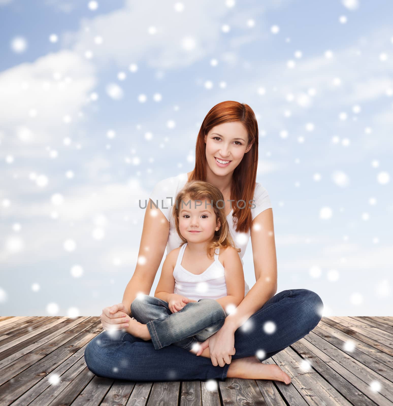 childhood, parenting and people concept - happy mother with little girl over wooden floor and blue sky background