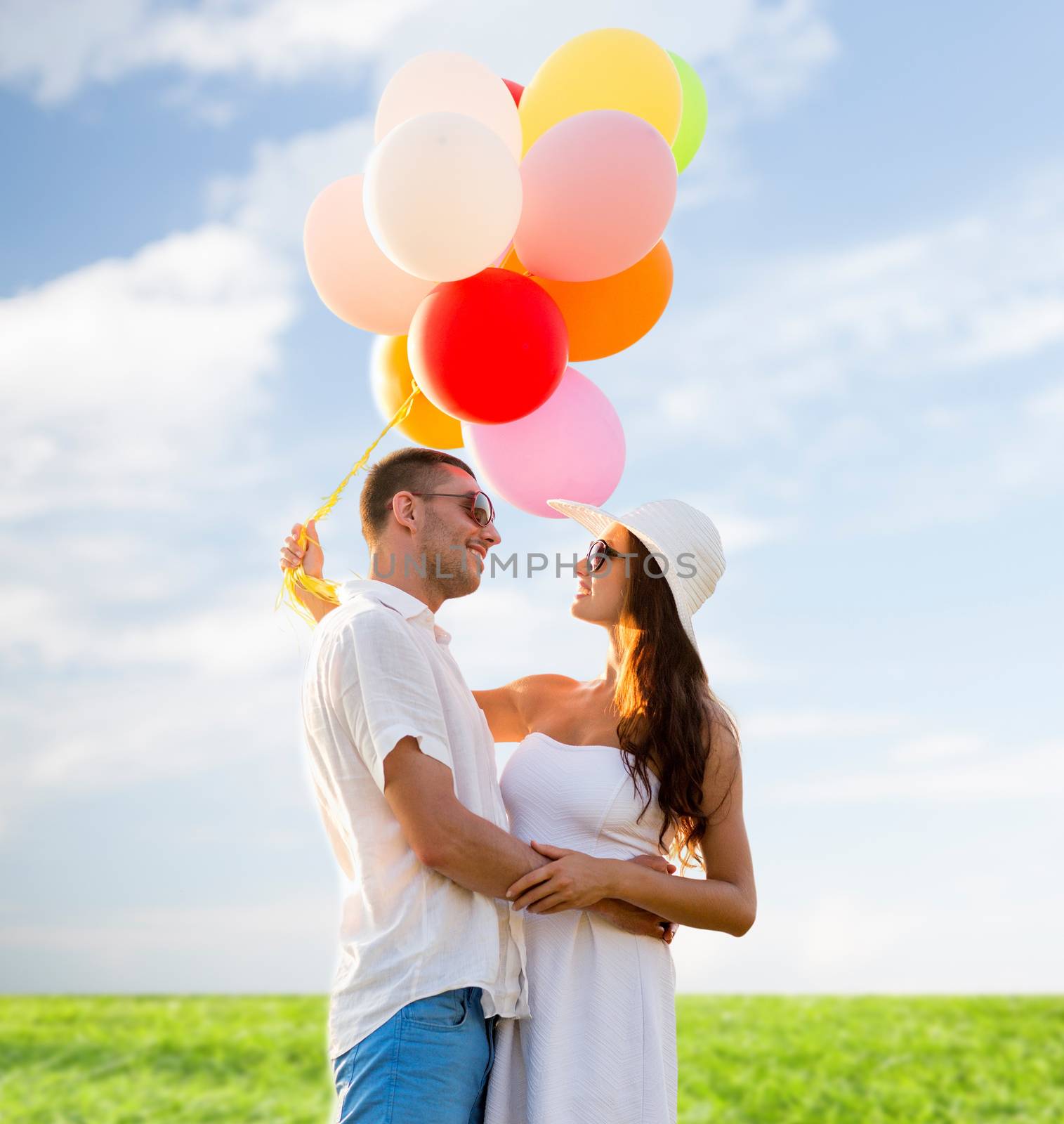 love, wedding, summer, dating and people concept - smiling couple wearing sunglasses with balloons hugging over blue sky and grass background