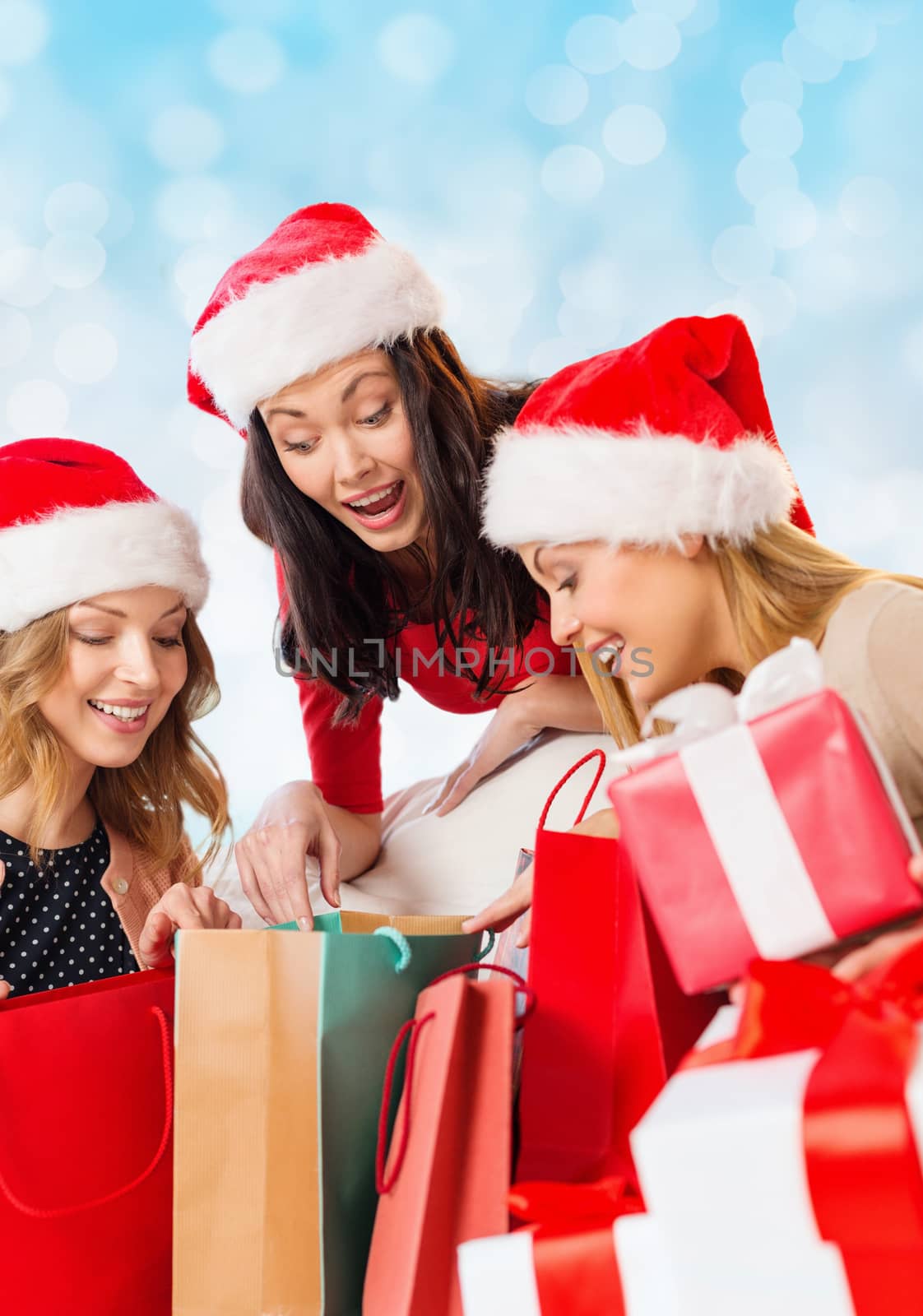 smiling young women in santa hats with gifts by dolgachov