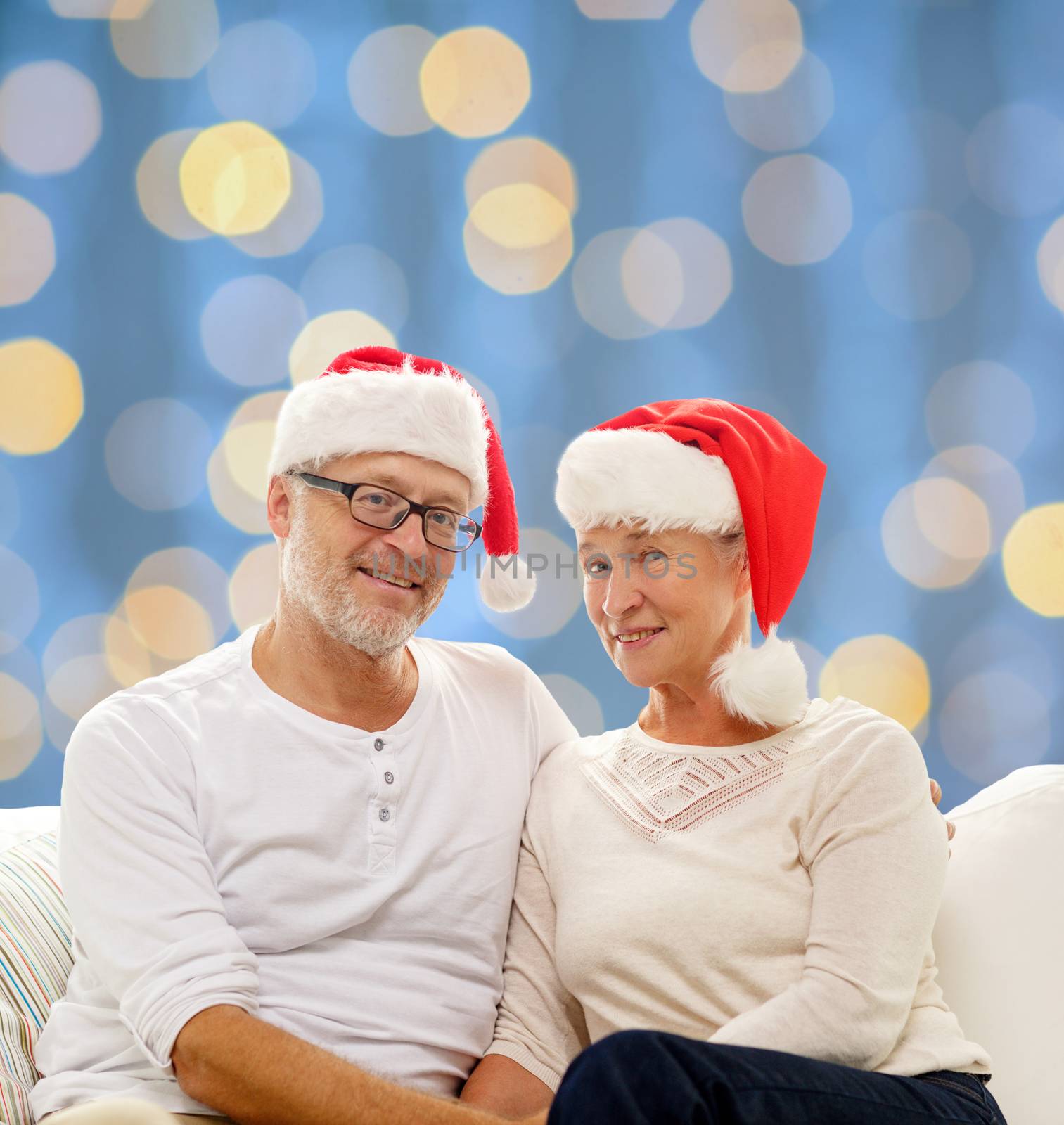 happy senior couple in santa helper hats by dolgachov