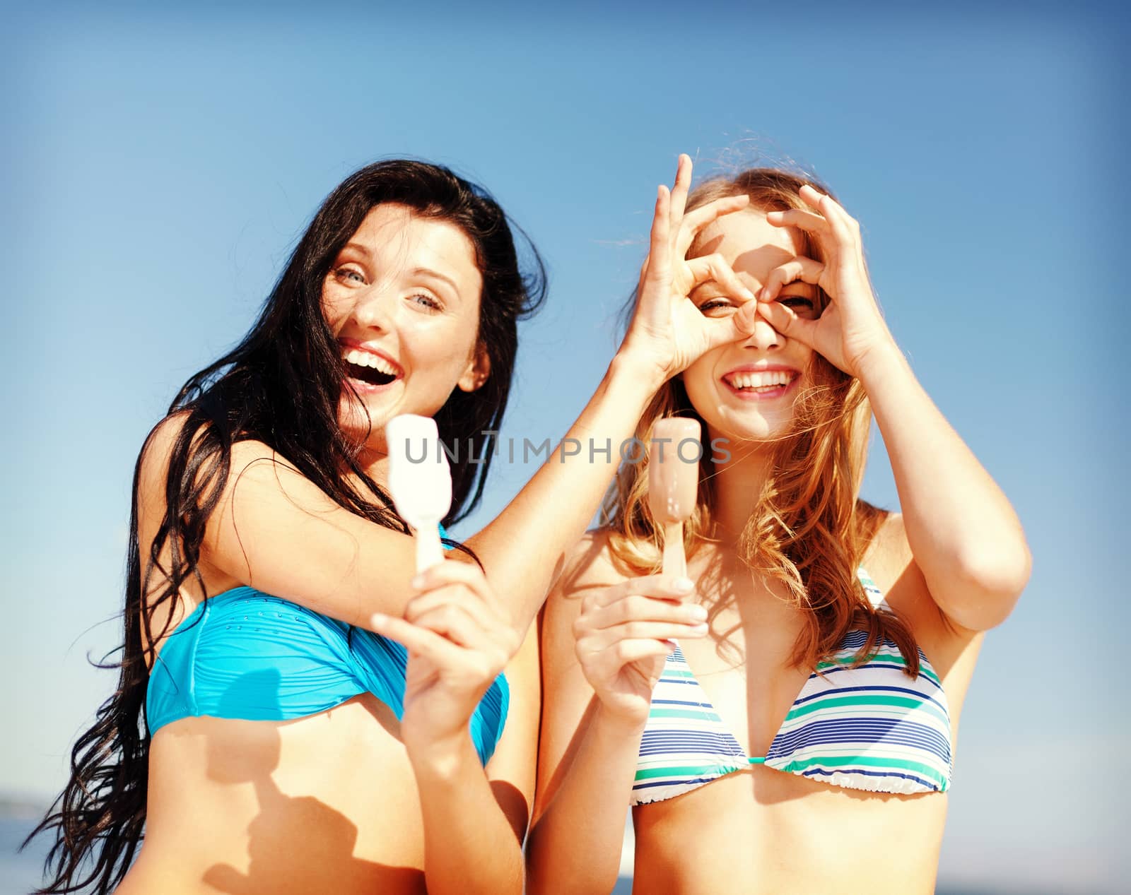 summer holidays and vacation - girls in bikinis eating ice cream on the beach