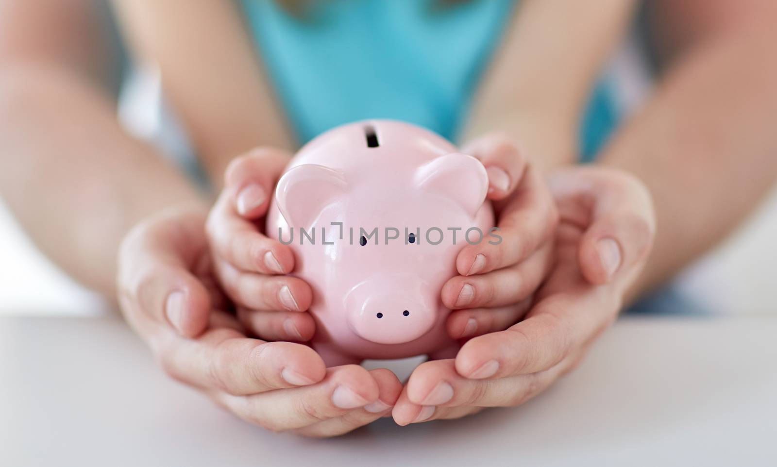 close up of family hands with piggy bank by dolgachov