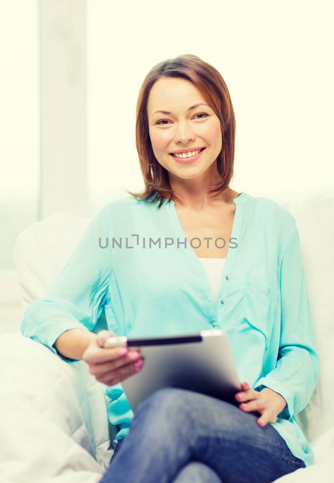 home, technology and internet concept - smiling woman sitting on the couch with tablet pc at home