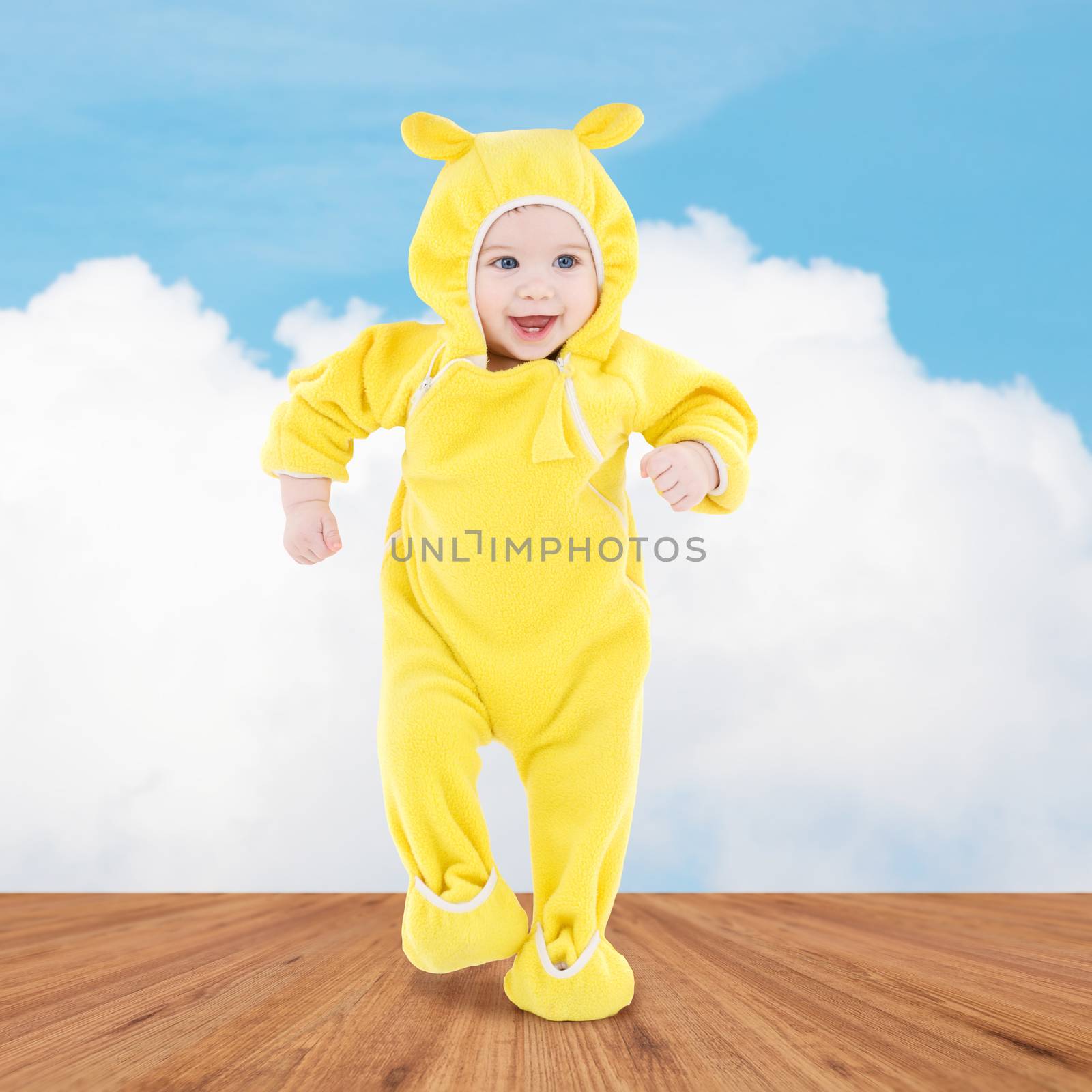 people, children, achievement and happiness concept - happy baby in yellow suit making first steps over wooden floor and blue sky background