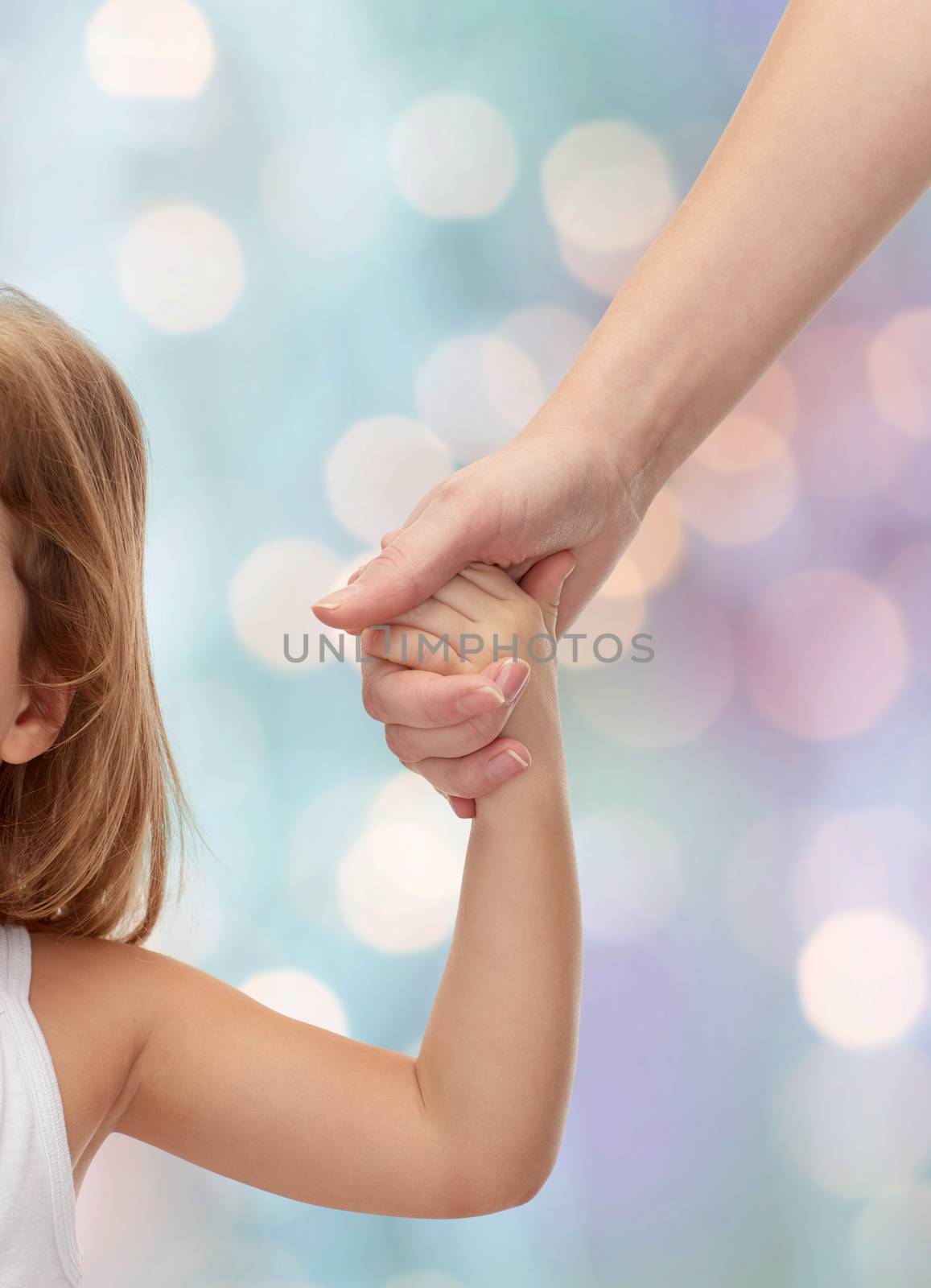 people, charity, family and adoption concept - close up of woman and little girl holding hands over holiday lights background