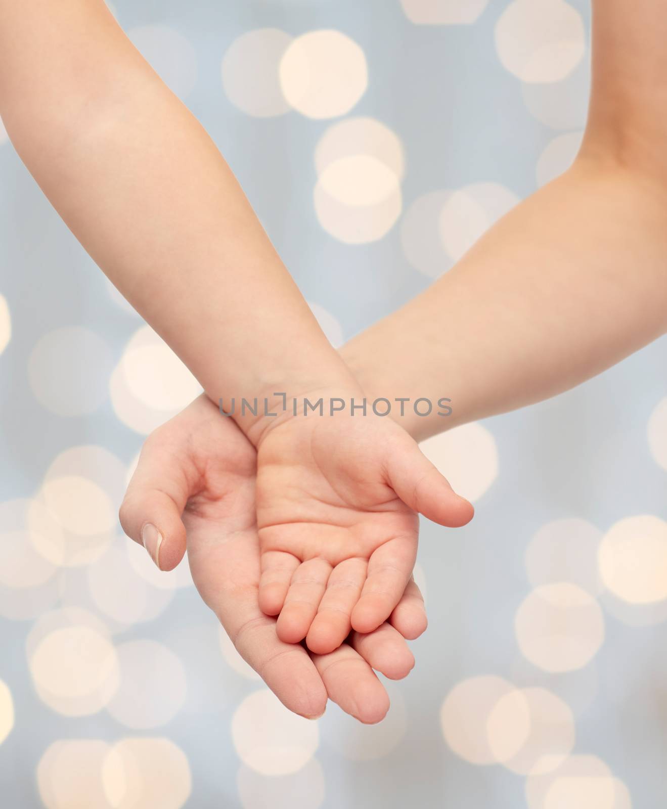 people, charity, family, children and advertisement concept - close up of woman and little child hands holding empty palms over holiday lights background