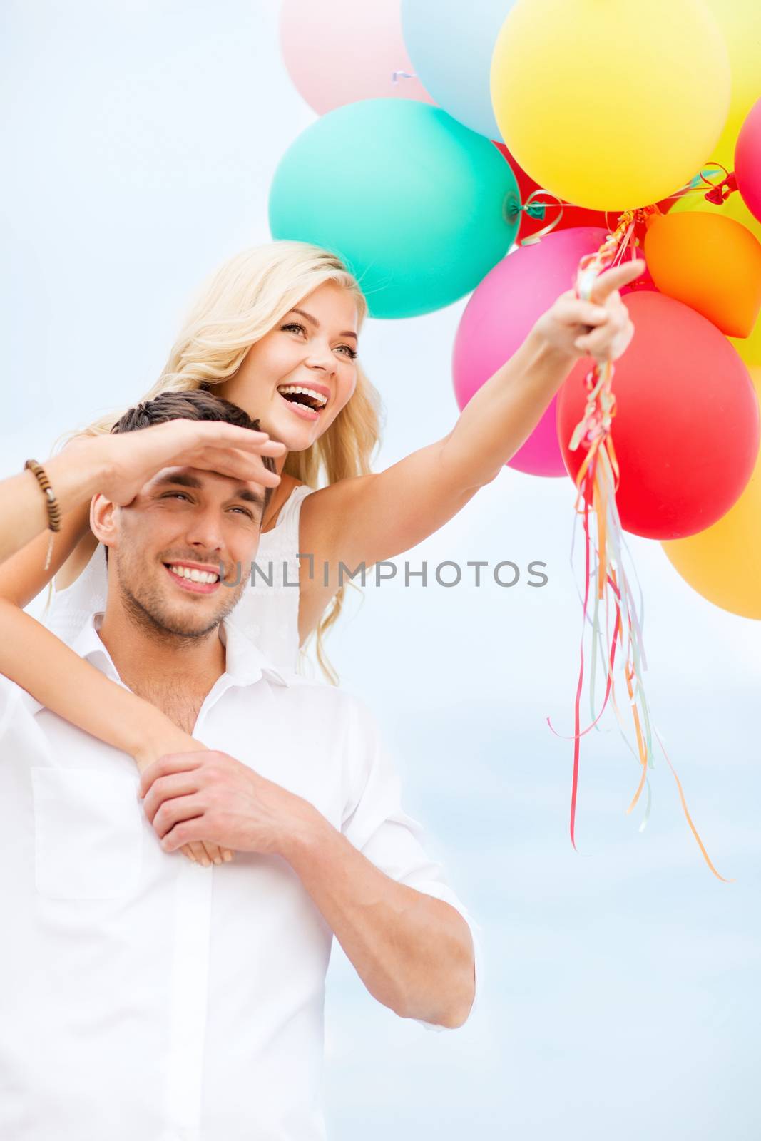 summer holidays, celebration and dating concept - couple with colorful balloons at seaside