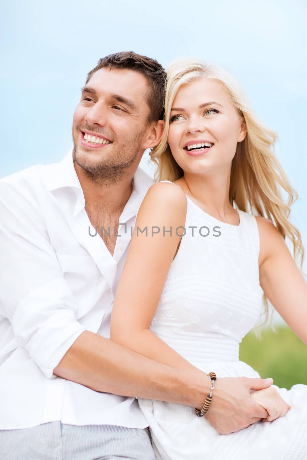 summer holidays and dating concept - couple in shades sitting at sea side