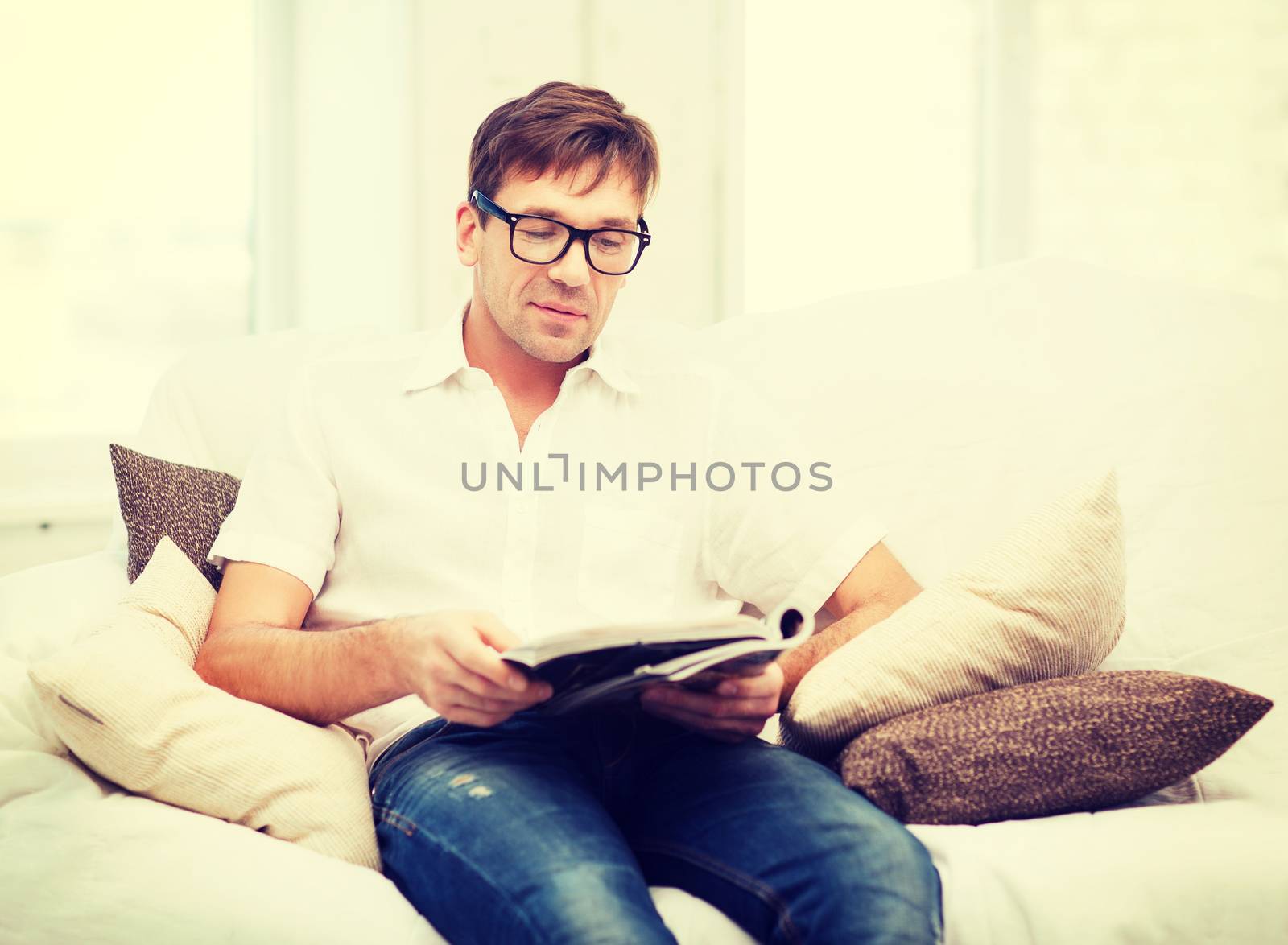 man with magazine at home by dolgachov