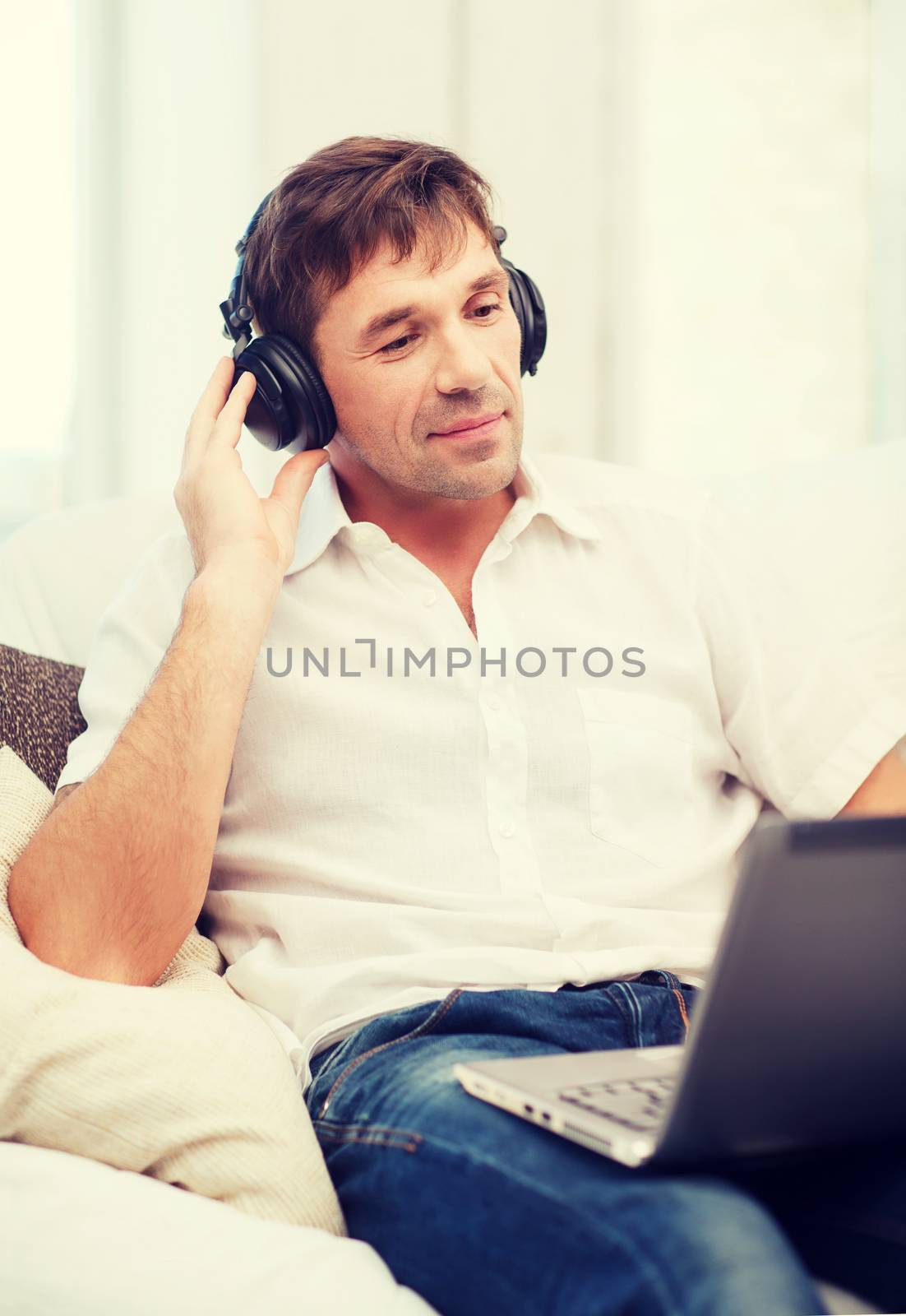 technology, leisure and lifestyle concept - happy man with headphones listening to music at home