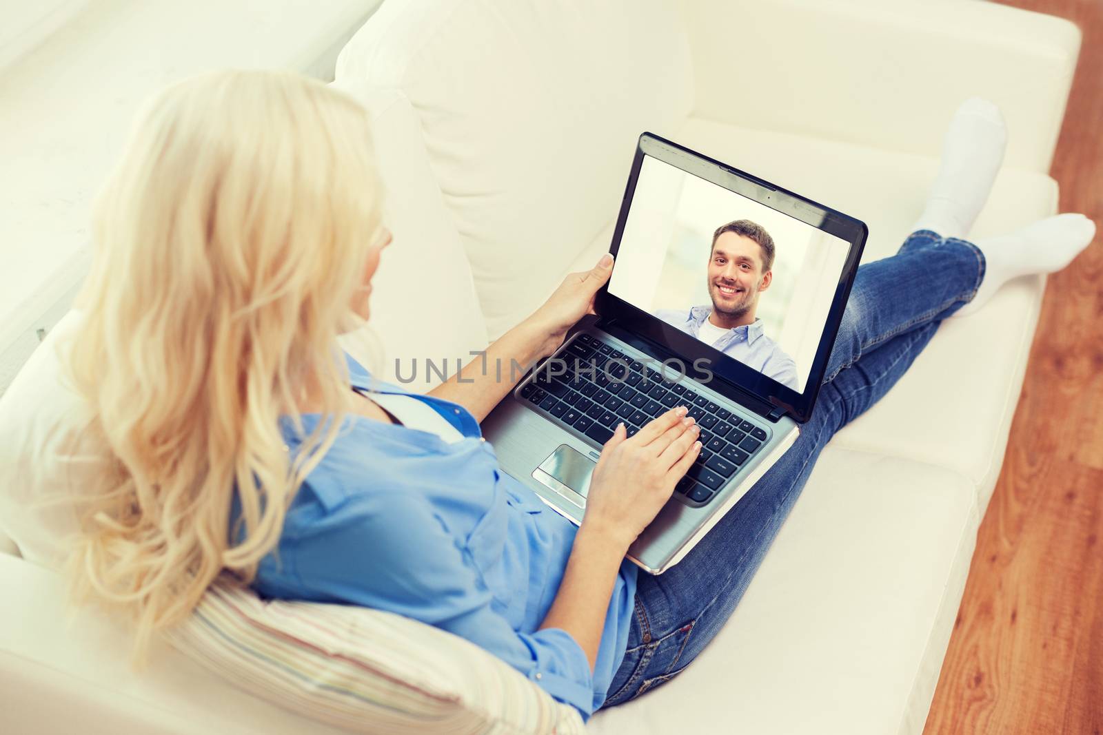 smiling woman with laptop computer at home by dolgachov