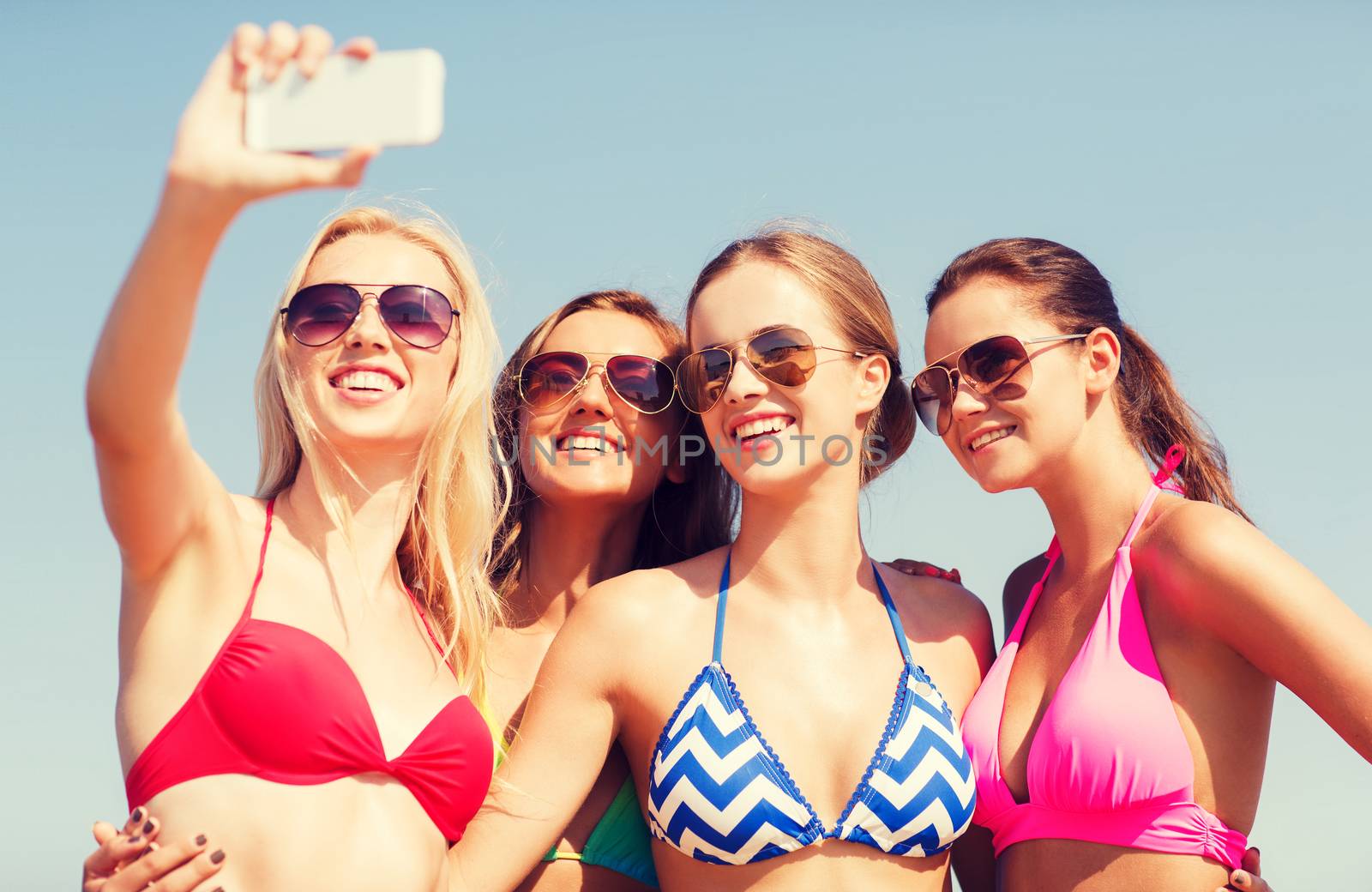 group of smiling women making selfie on beach by dolgachov