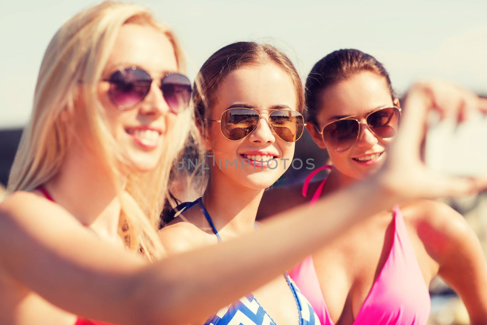 group of smiling women making selfie on beach by dolgachov