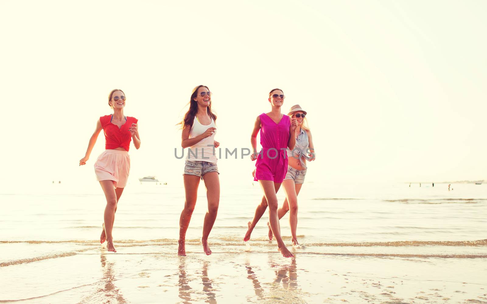 group of smiling women running on beach by dolgachov