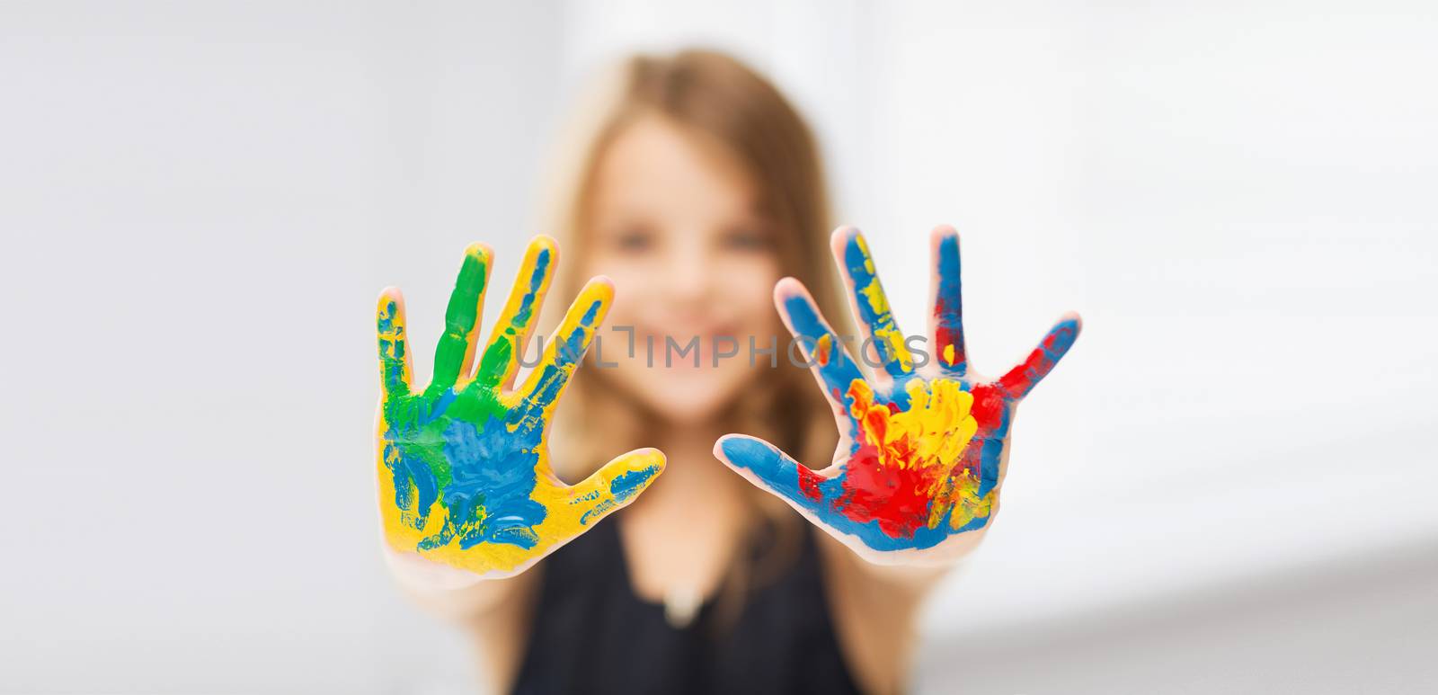 education, school, art and painitng concept - little student girl showing painted hands