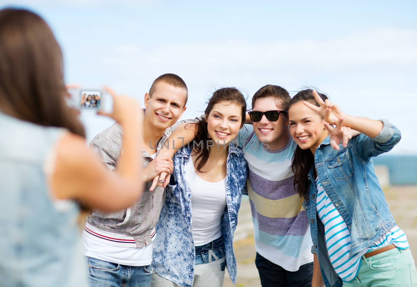 summer holidays and technology concept - group of teenagers taking photo outside