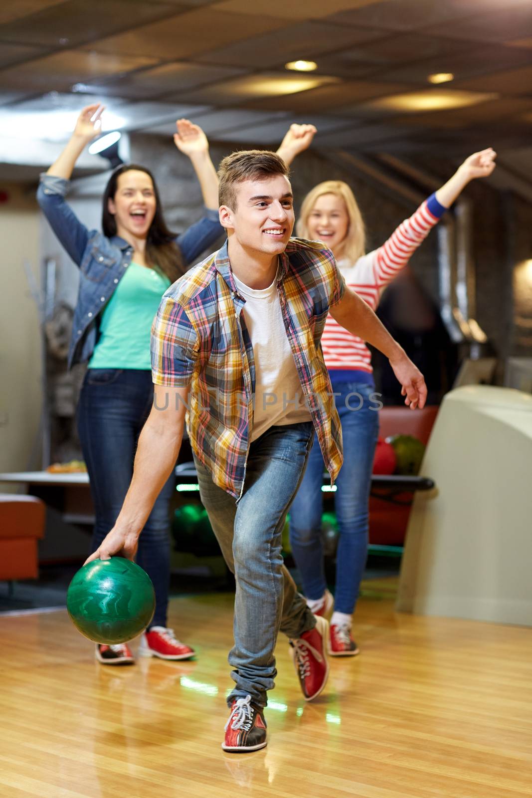happy young man throwing ball in bowling club by dolgachov