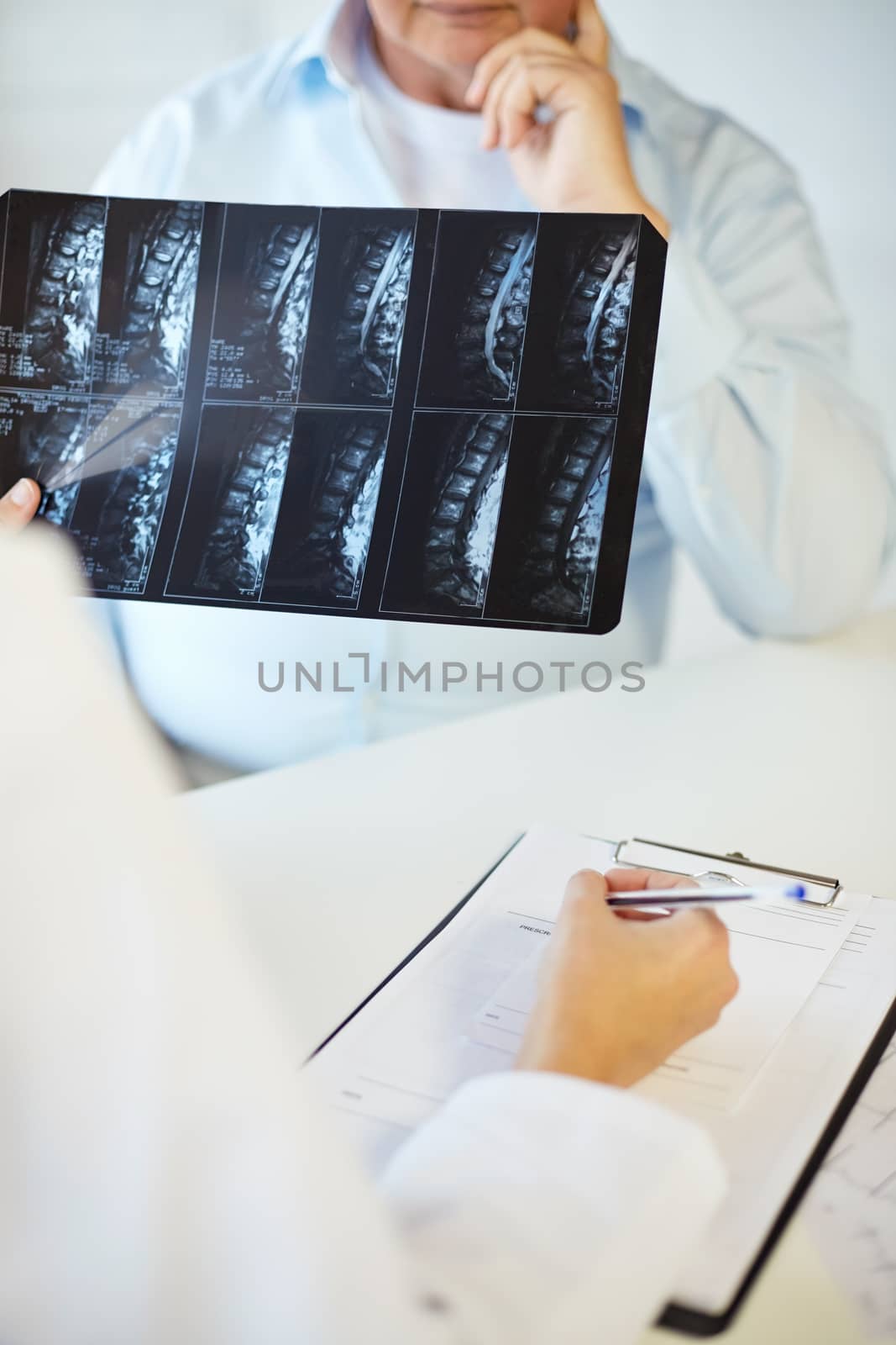medicine, age, health care and people concept - close up of senior male patient and doctor with x-ray and clipboard in hospital