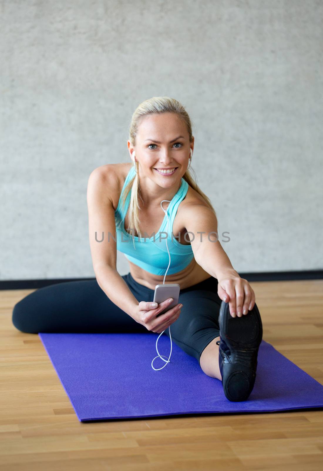smiling woman stretching leg on mat in gym by dolgachov