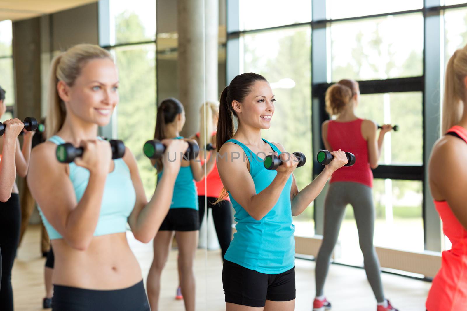 group of women with dumbbells in gym by dolgachov