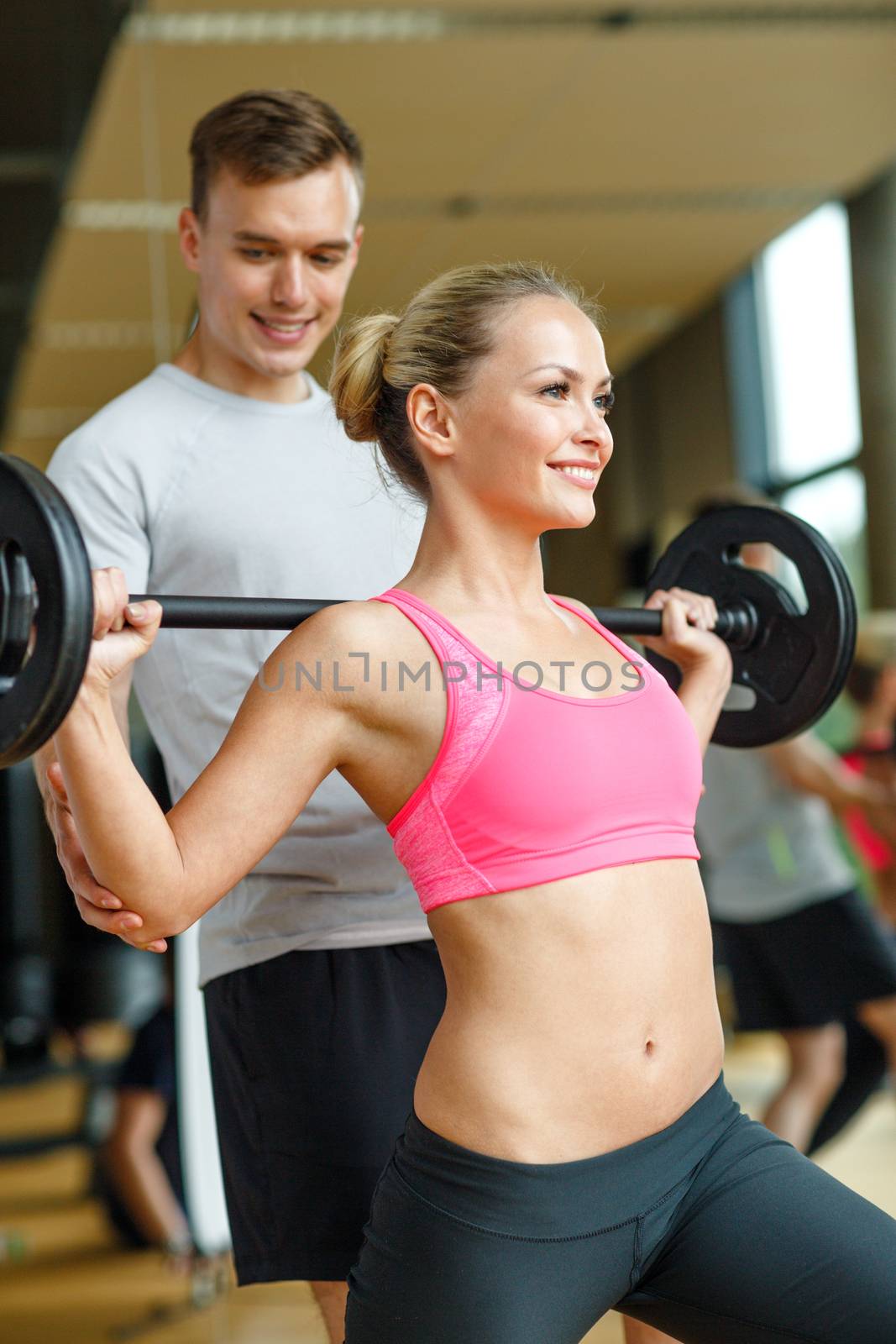 smiling man and woman with barbell in gym by dolgachov