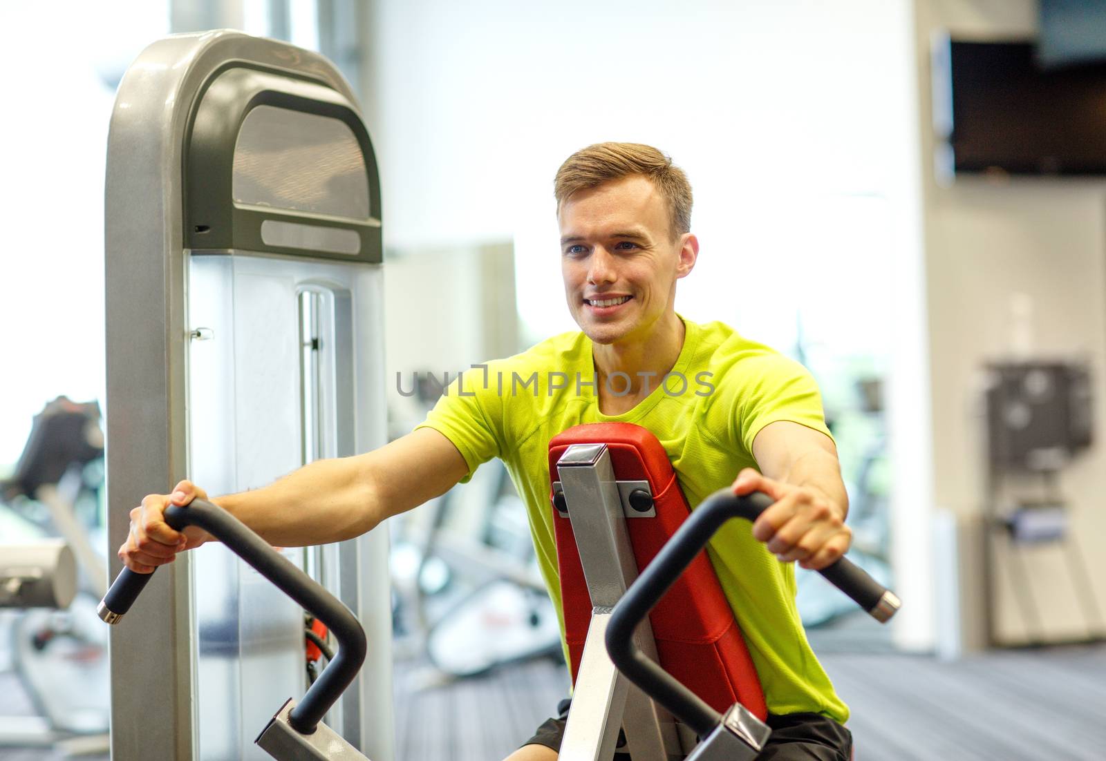 smiling man exercising in gym by dolgachov