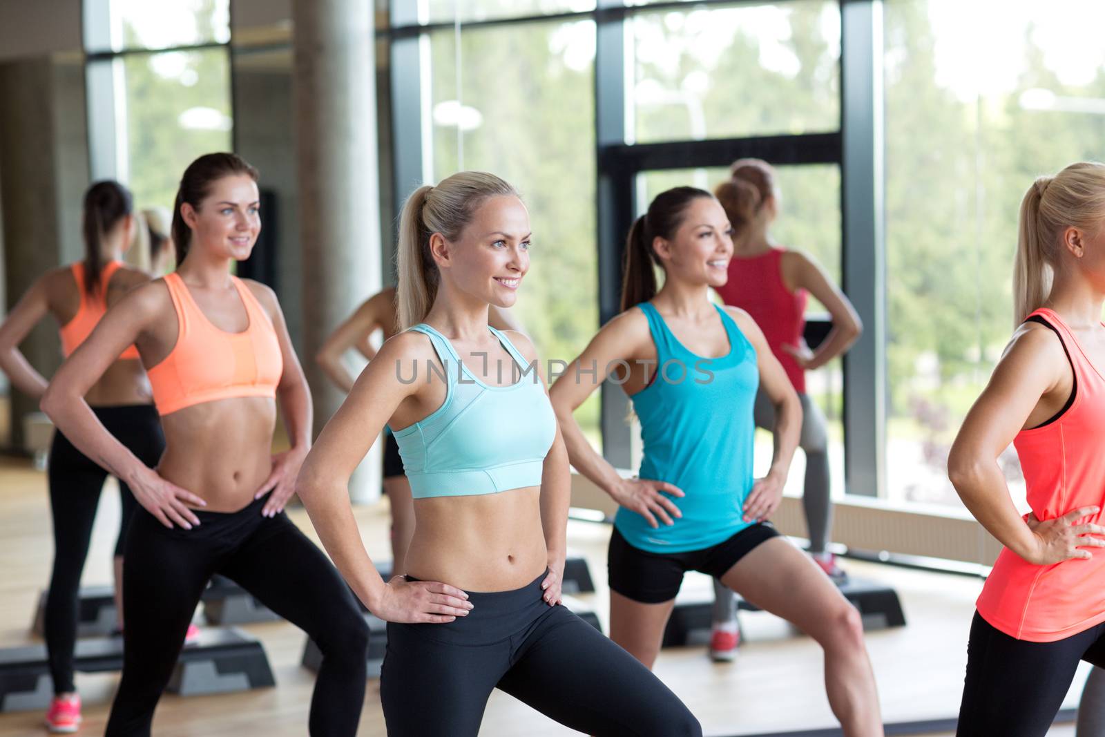 group of women working out with steppers in gym by dolgachov